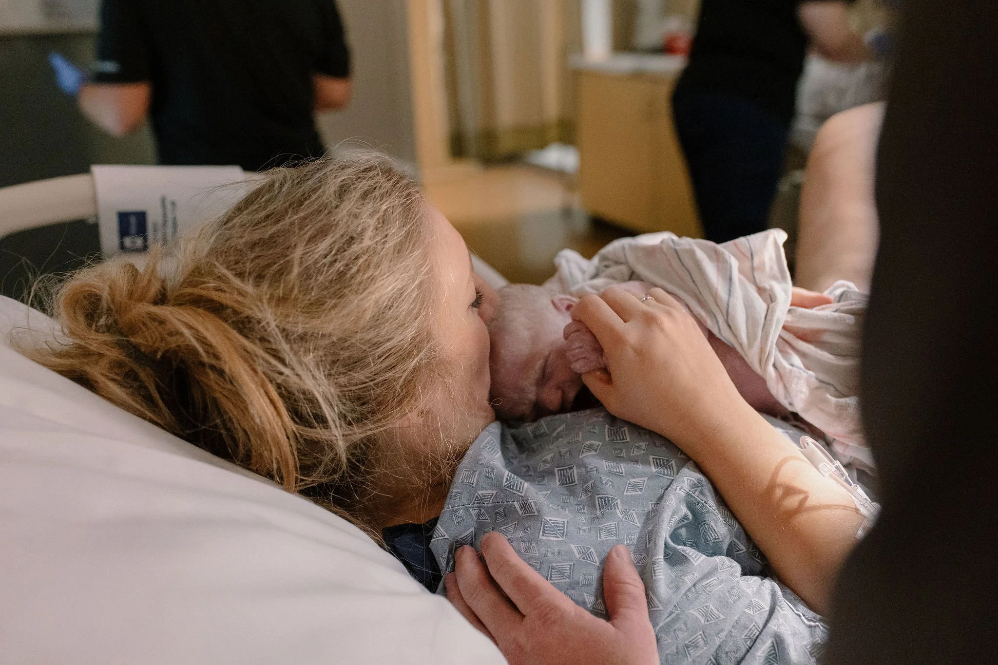 mom kissing newborn baby immediately after hospital birth