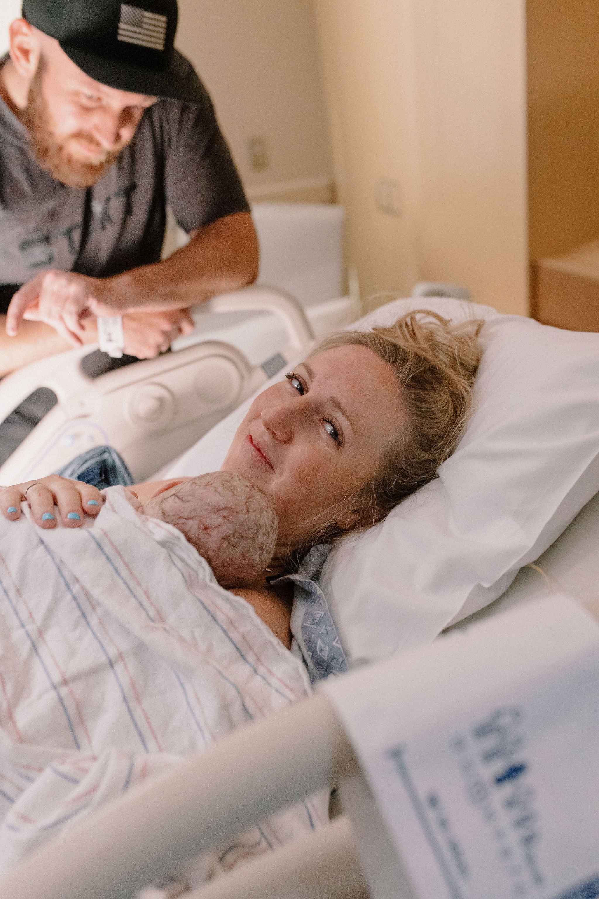 dad admiring mom holding newborn baby in hospital birth photography session