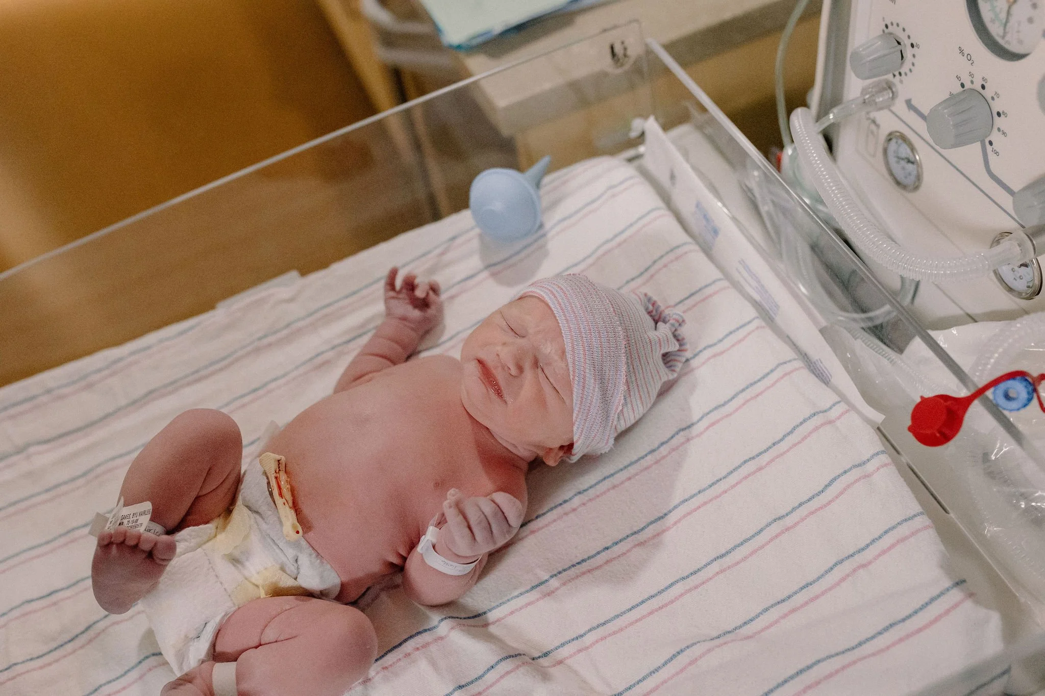 Newborn baby boy laying in warmer in hospital room immediately after birth