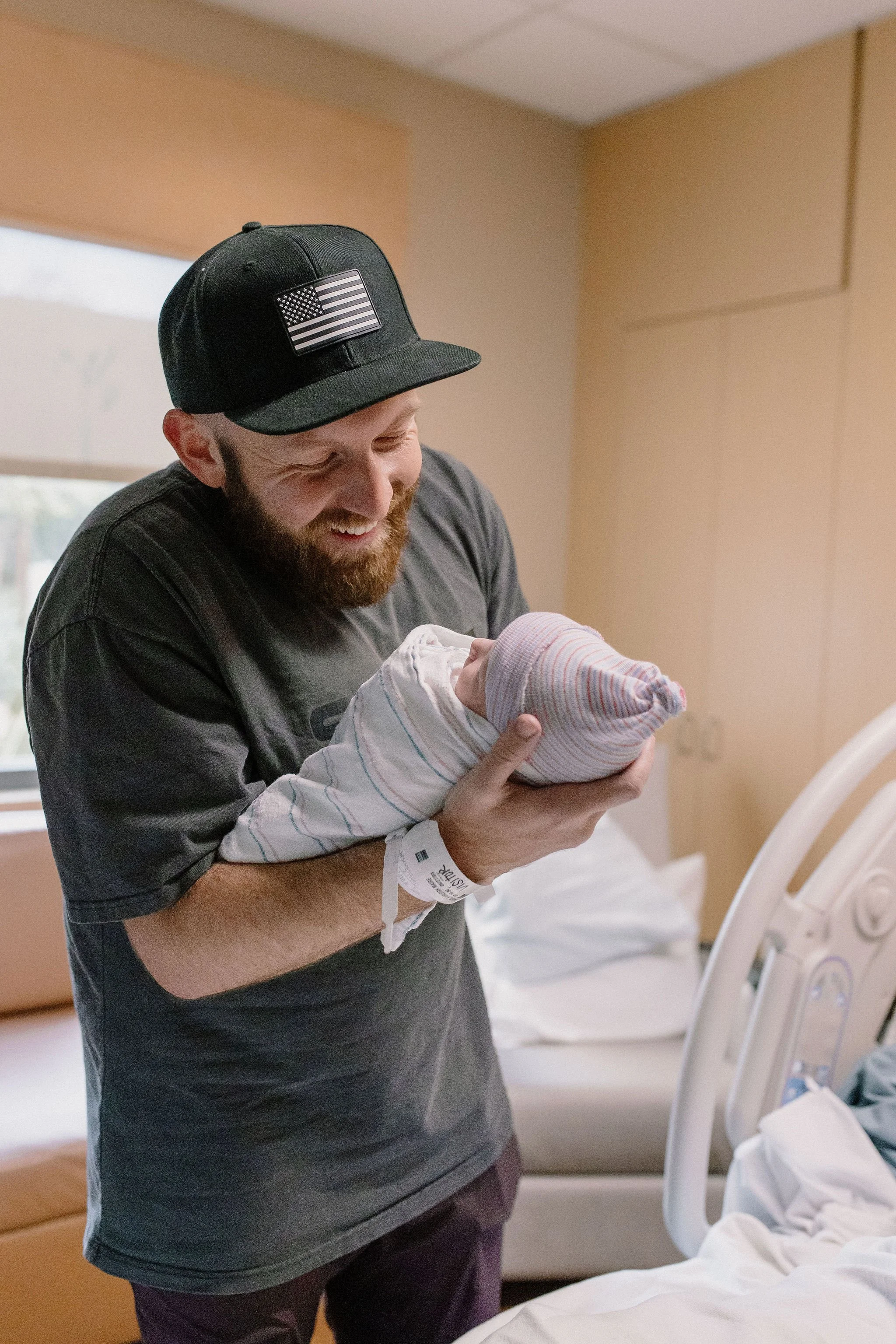 dad holding swaddled newborn baby in hospital after birth