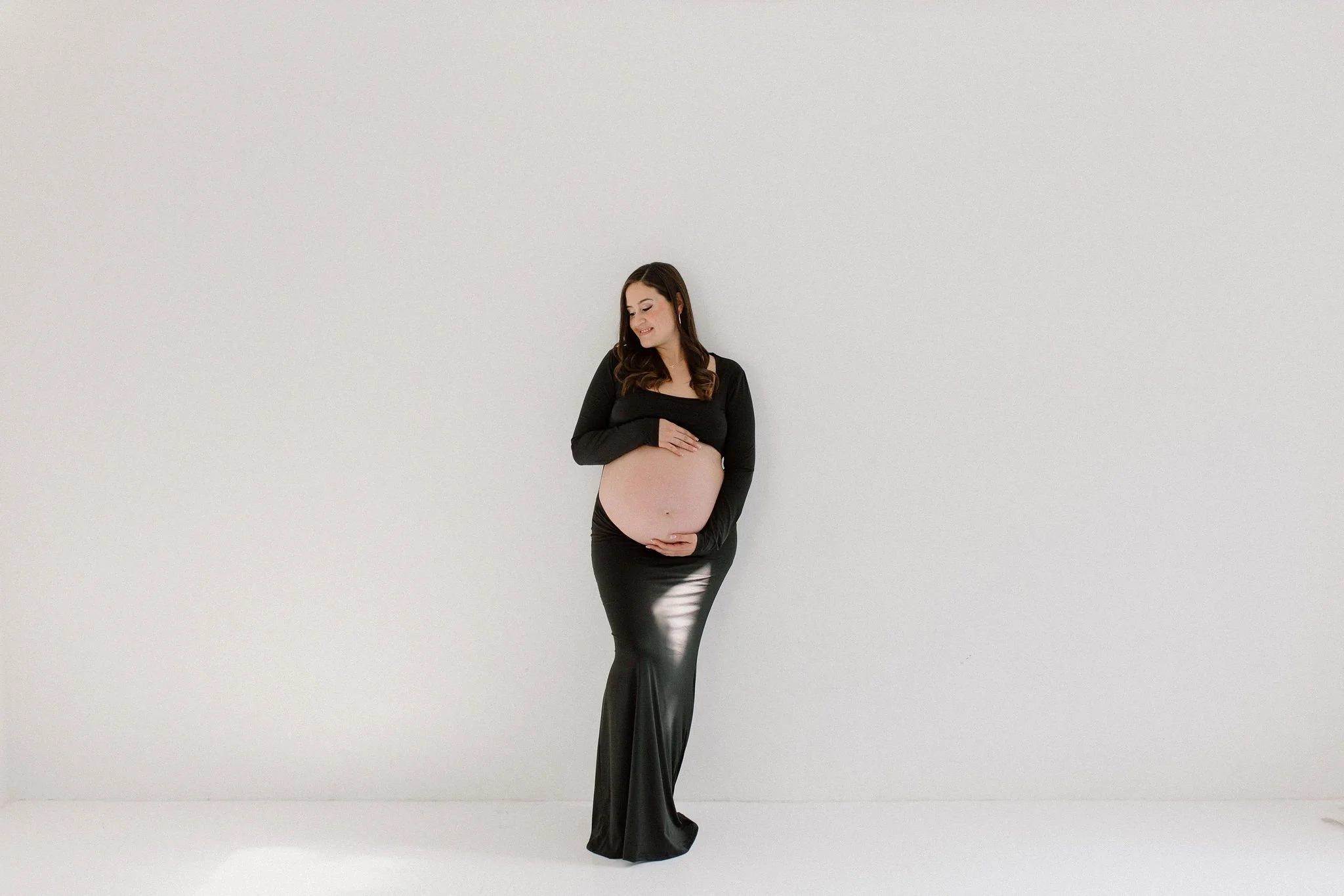 pregnant mom holding belly in studio maternity photoshoot in Gilbert, Arizona