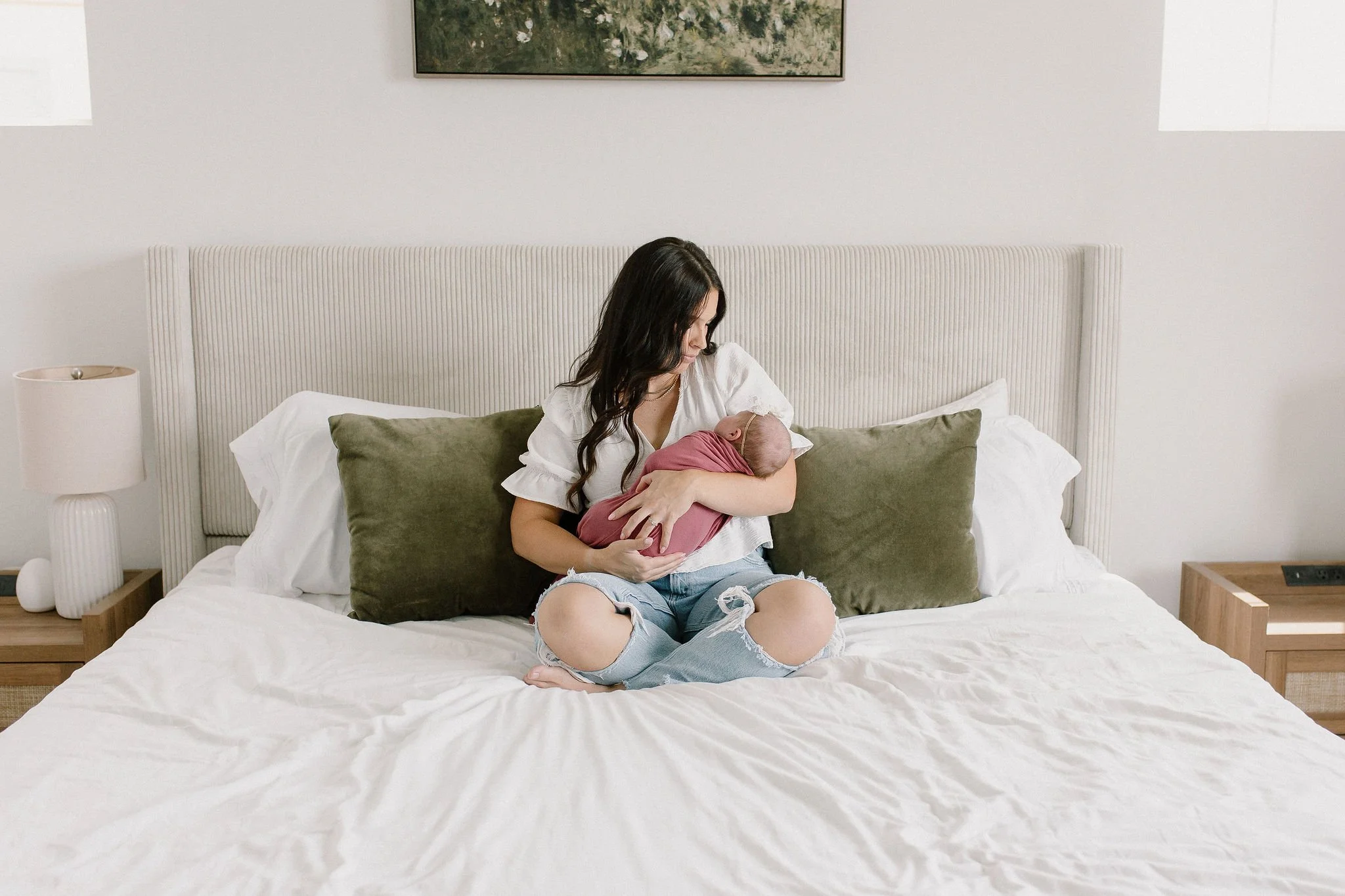 mom holding baby on bed in natural light bedroom newborn photos