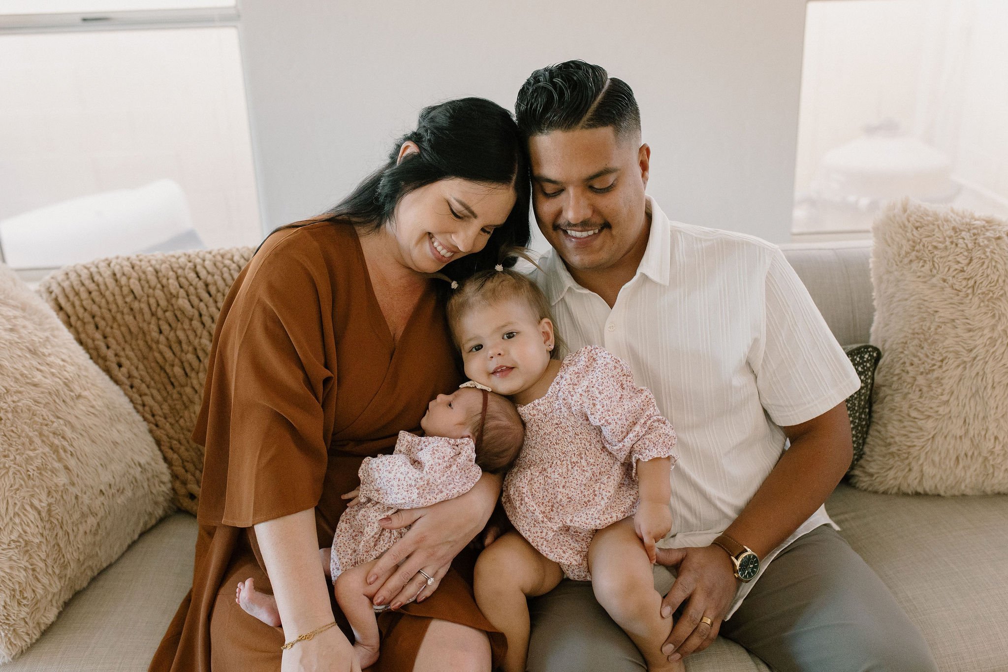 family sitting on couch with newborn in neutral living room lifestyle family photography in Gilbert Arizona