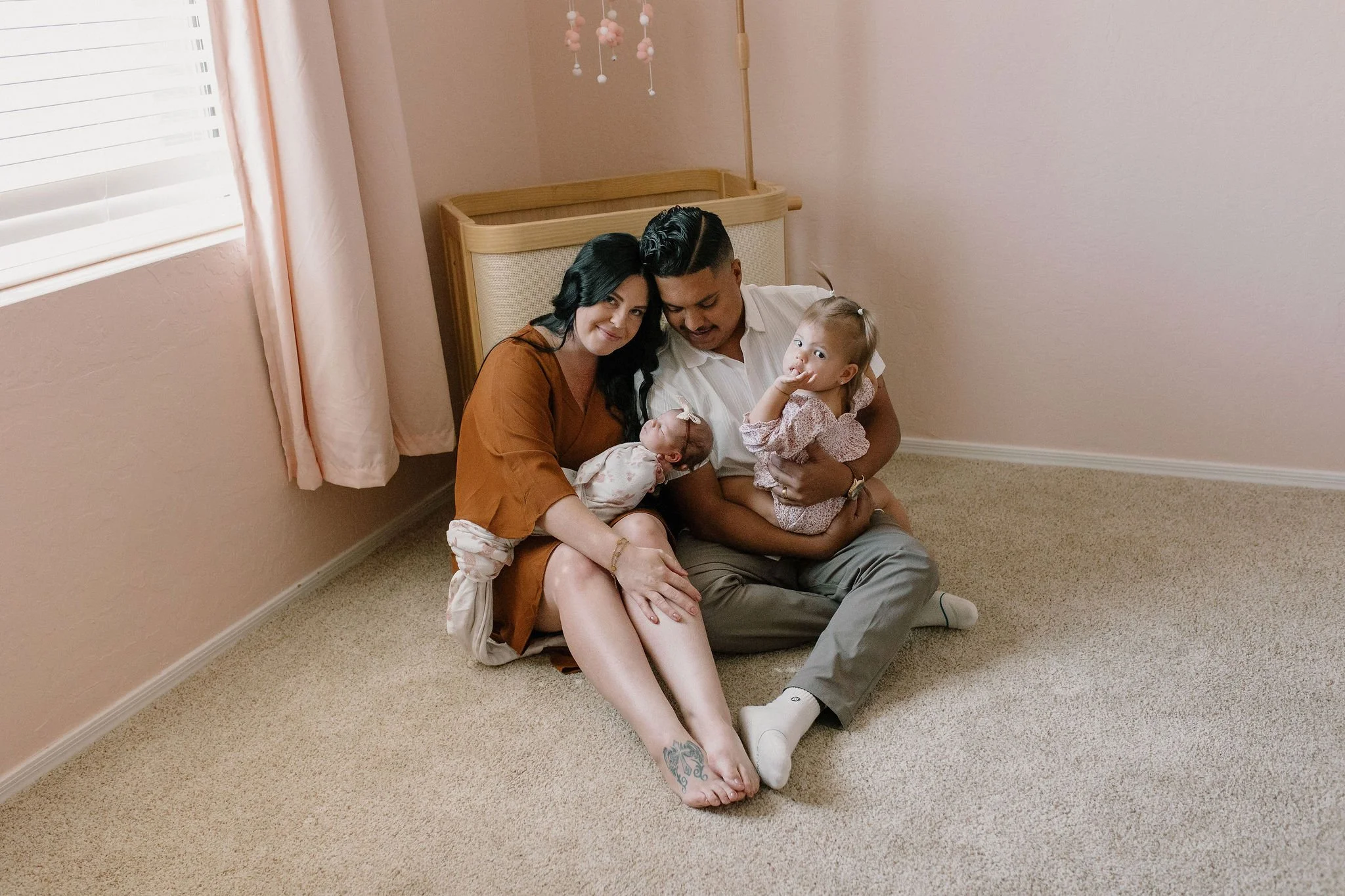 family sitting together in pink baby nursery in-home newborn photography session in Gilbert, Arizona