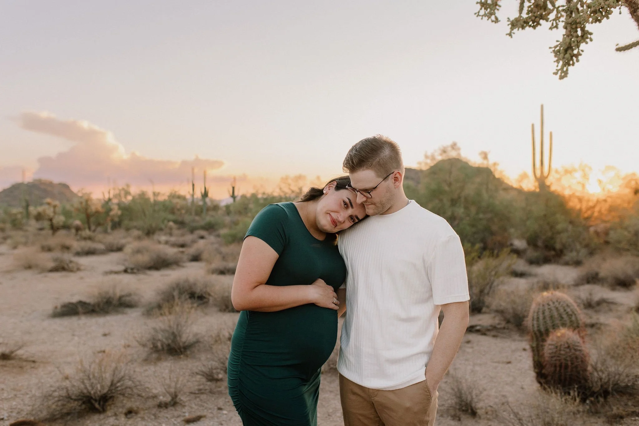 pregnant mom holding belly laying her head on dad's shoulder in desert maternity photoshoot in Gilbert, Arizona