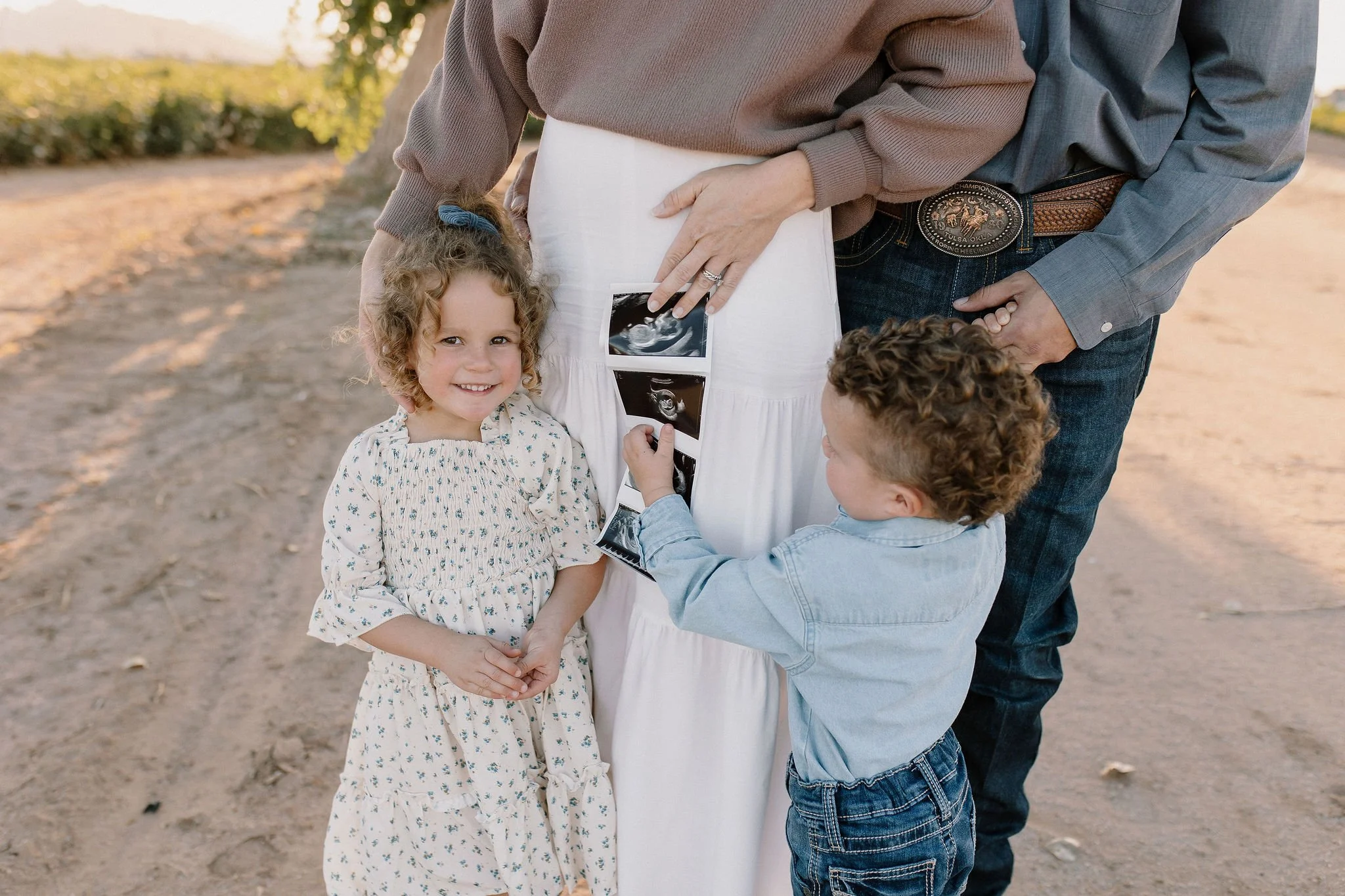pregnant mom holding ultrasound with kids looking in Gilbert maternity photoshoot