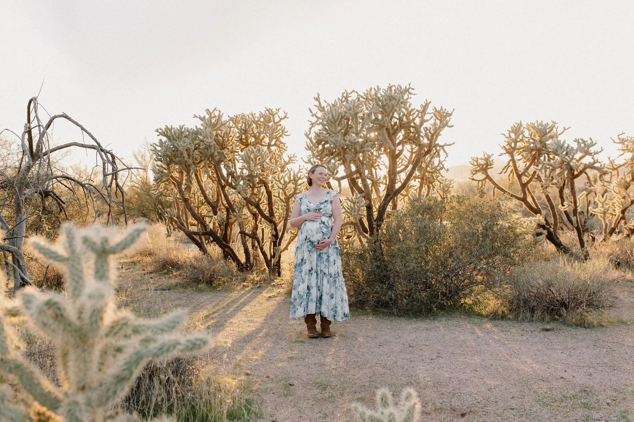 pregnant mom holding belly in the desert with cactus in Gilbert, Arizona