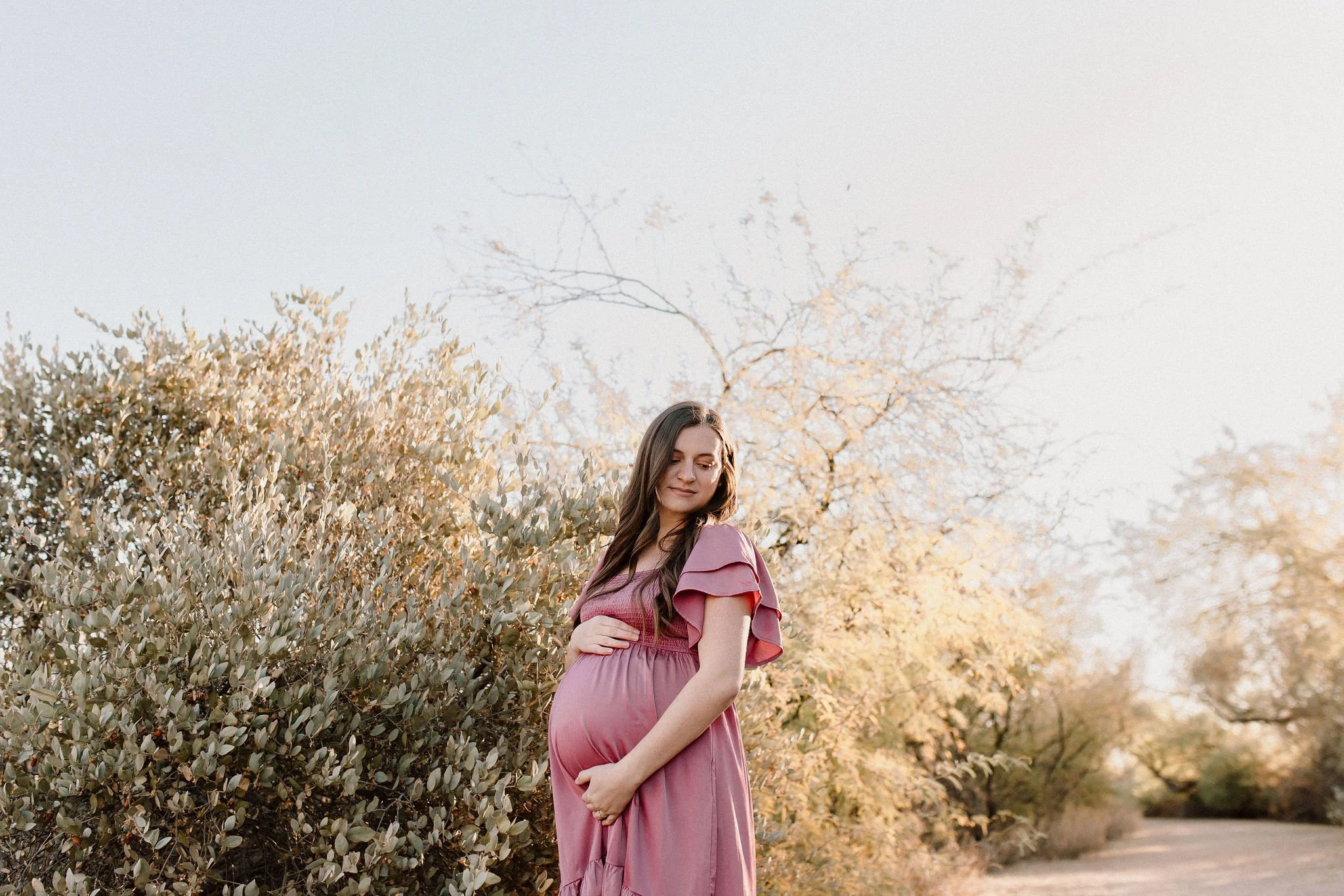 pregnant mom holding belly in Gilbert Arizona greenery