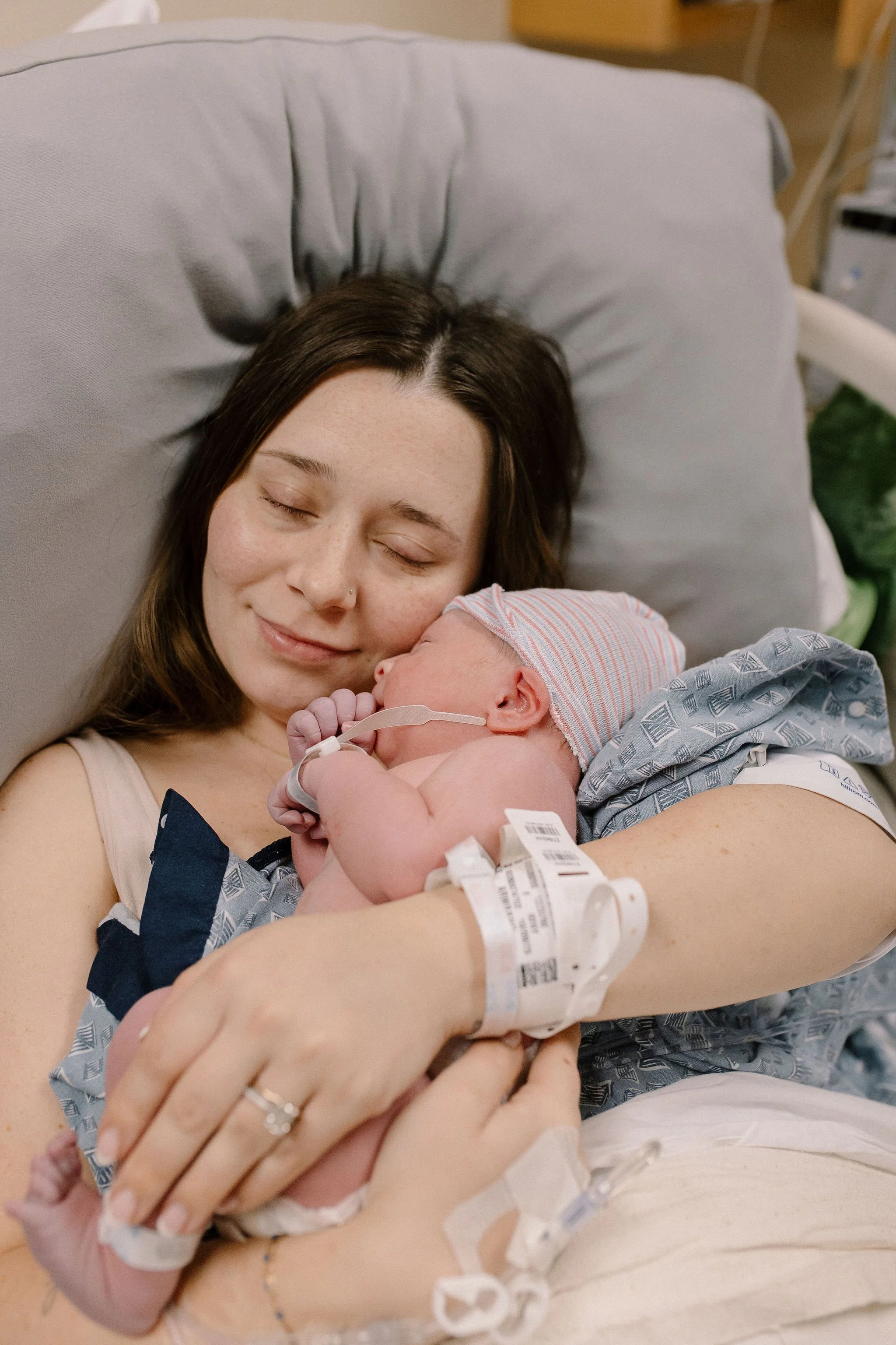 mom holding newborn baby in hospital birth photography session