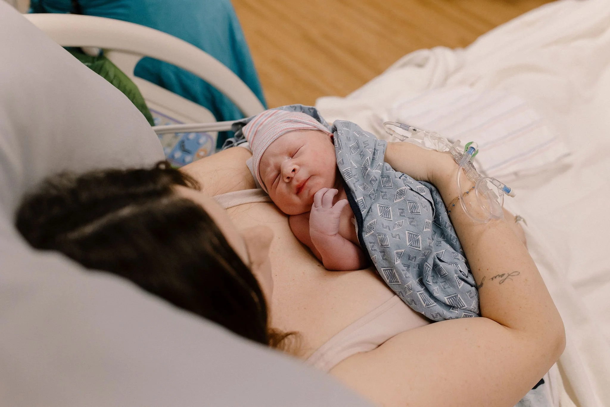 mom holding newborn baby in hospital bed in labor and delivery birth photography session Scottsdale AZ