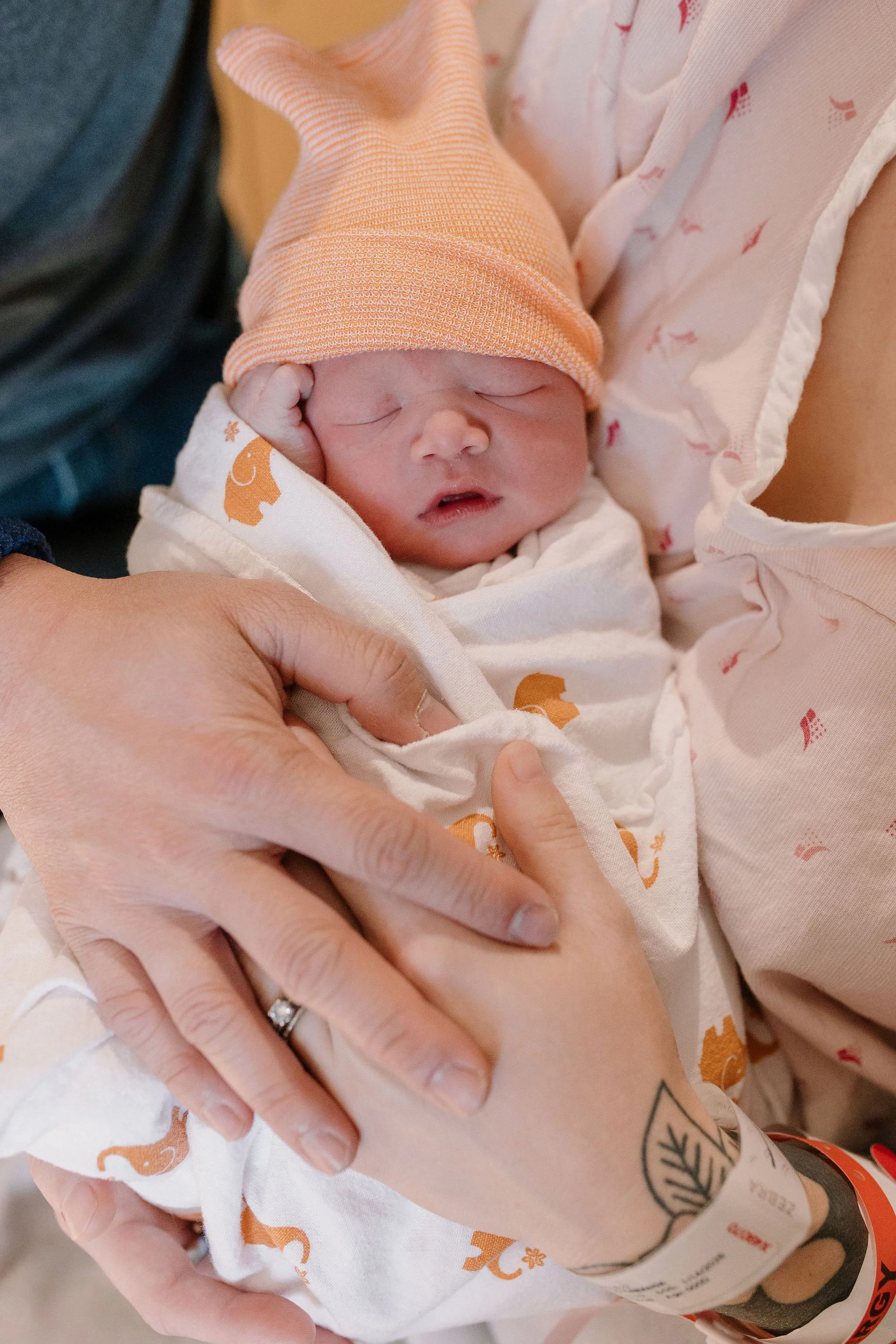 mom and dad holding swaddled newborn baby in birth photography session