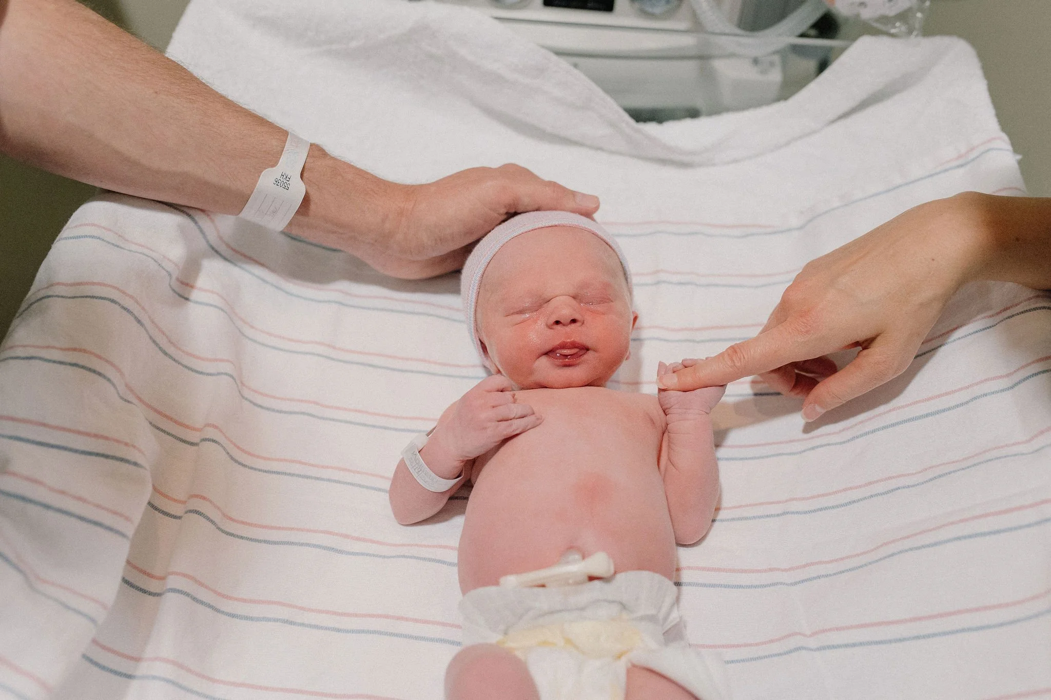 surrogate parents comforting newborn baby in warmer in birth photography session