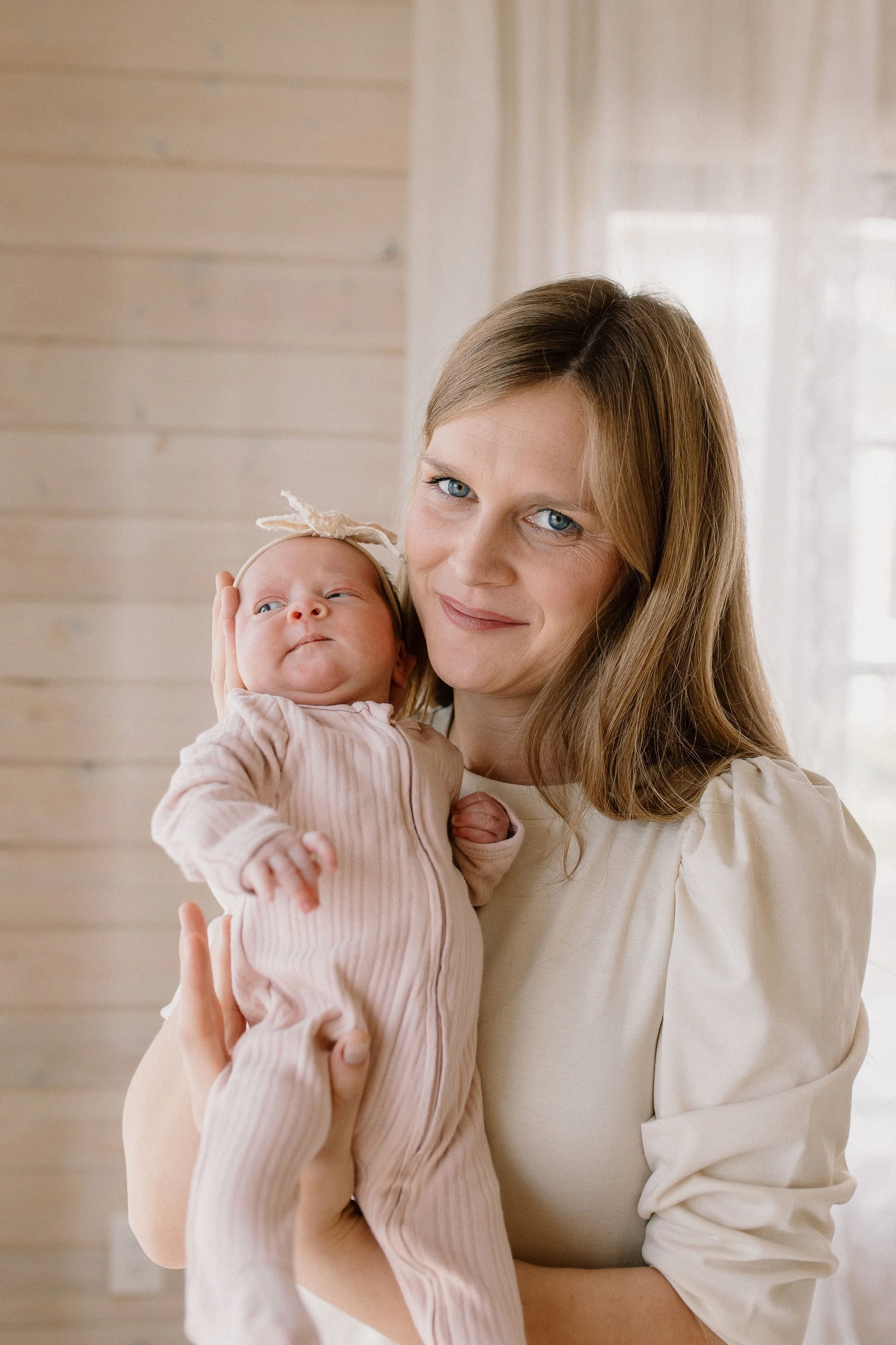 mom holds newborn baby in neutral studio space