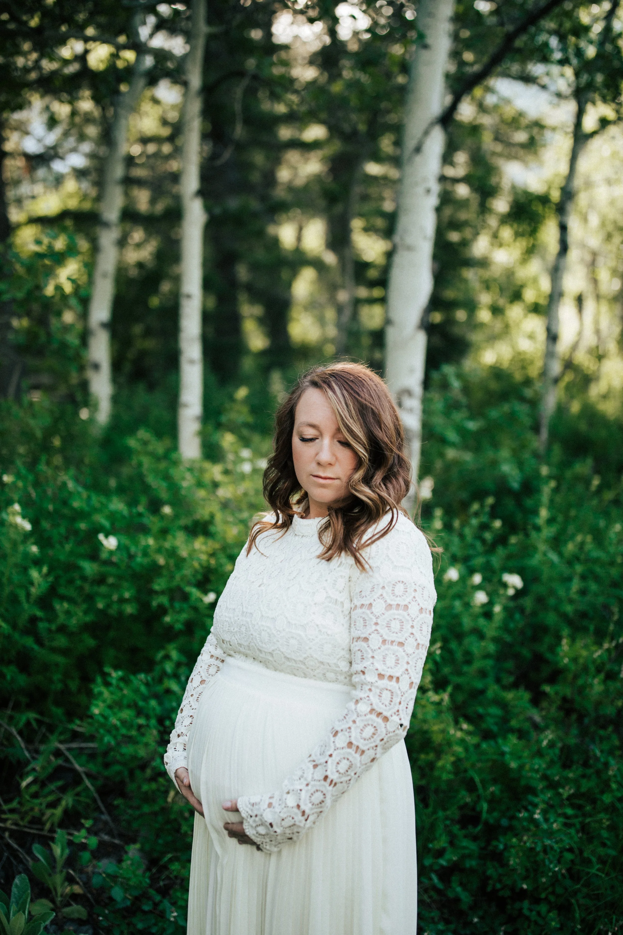 pregnant Mesa maternity photographer mom holding belly in green location