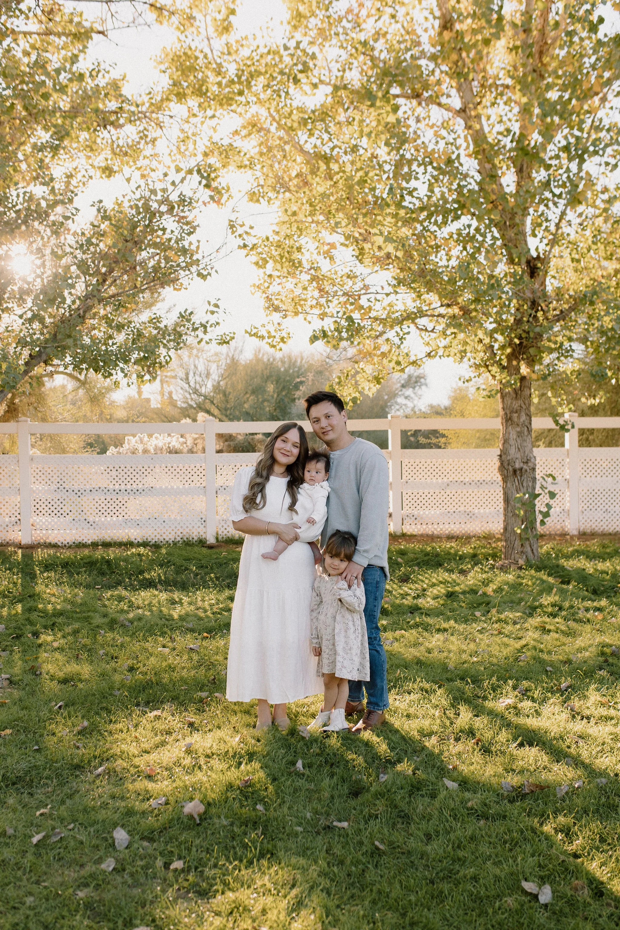 Family standing together smiling at Gilbert Arizona family photographer during fall mini sessions at Cottowoon Grove in Queen Creek