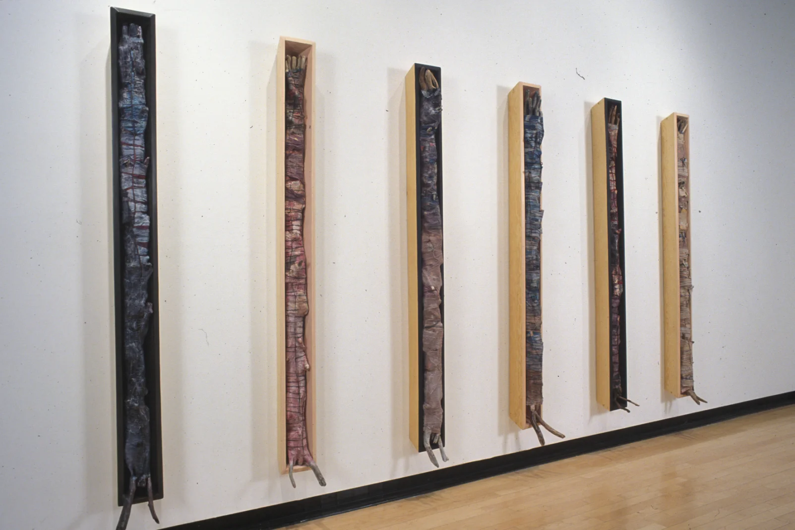 Rescue & Redemption installation view, 6 boxes, each box is 75"x8"x 8" wood, found sticks, cloth, ribbon, string, paint, wax, ephemera