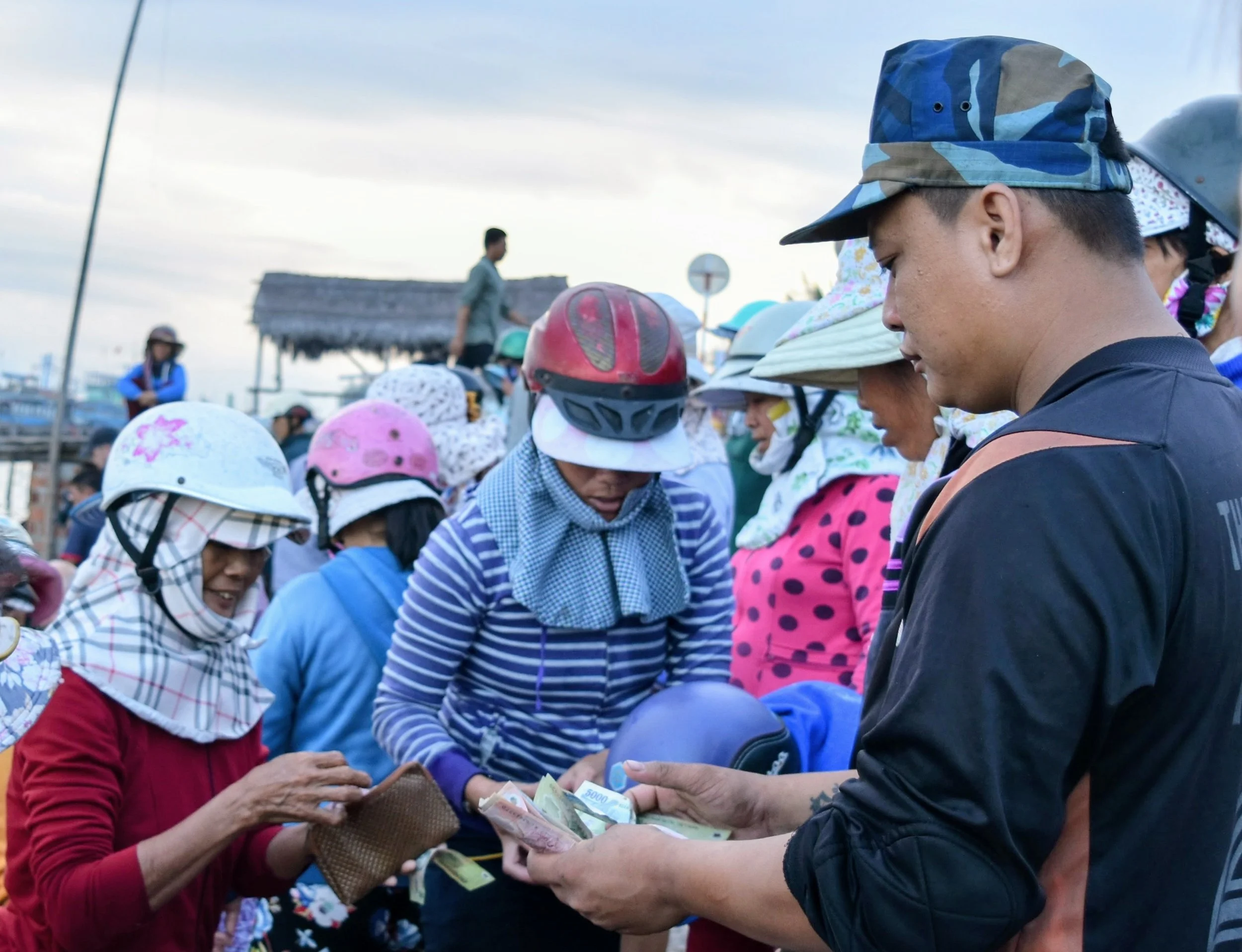 The chaos of women descending on the a man selling his catch for the day. Making deals very quickly. A fast paced tense scene.