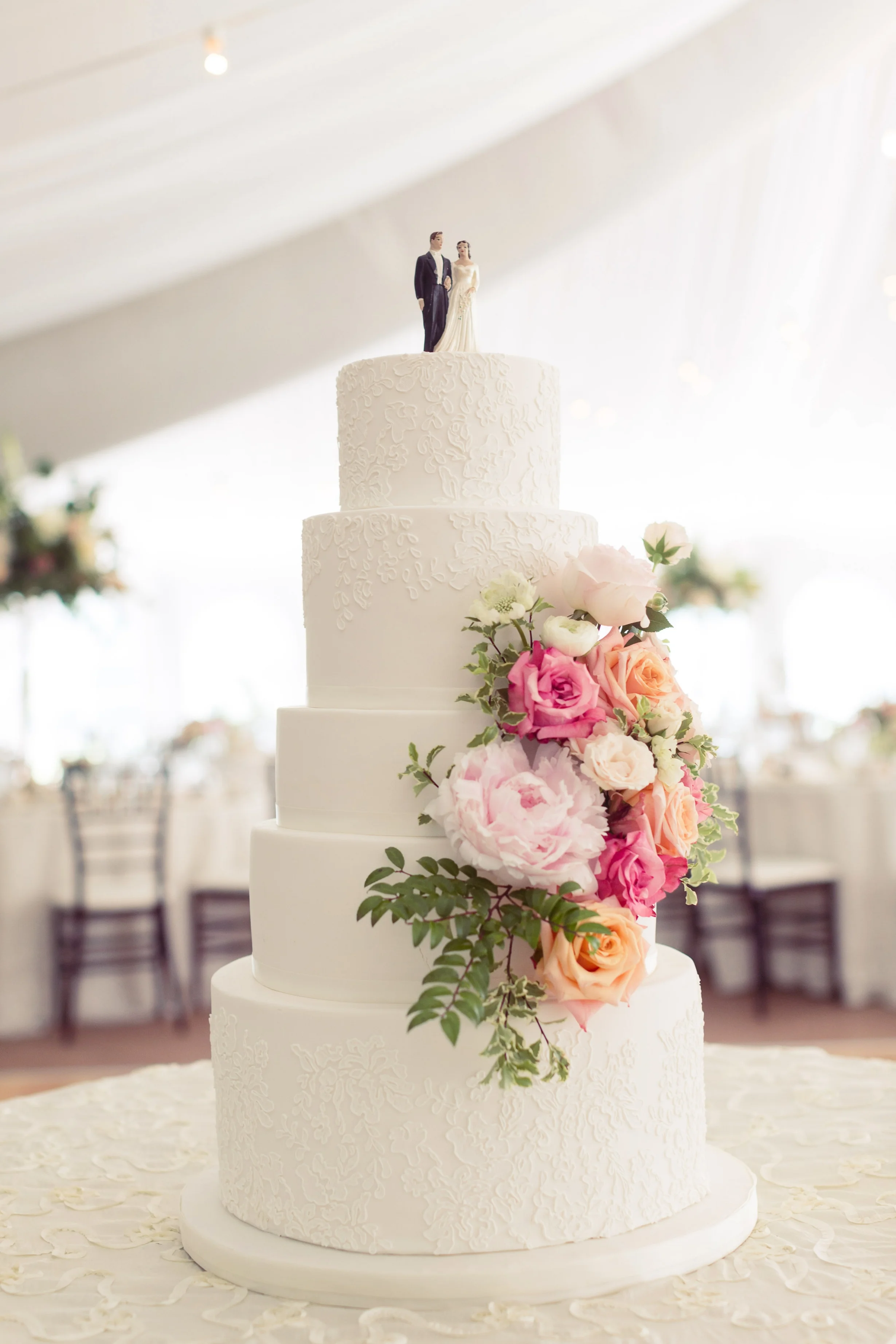 Five-tier white wedding cake with lace detail and fresh flowers. Photo by Kristen Taylor & Co.