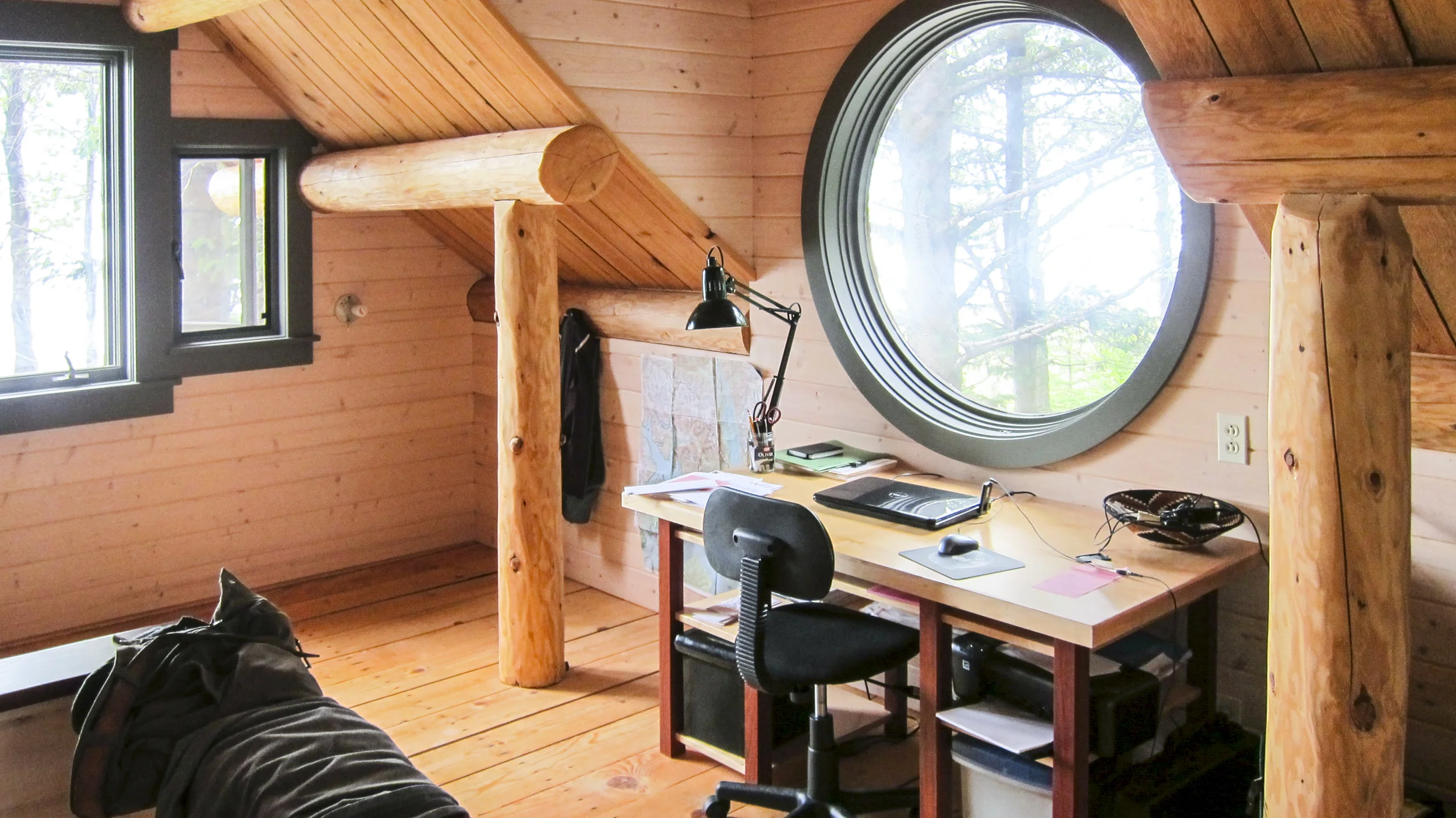 A loft with a round window in the Off the Grid Haines Cabin by Farrell Homebuilding LLC in Alaska 