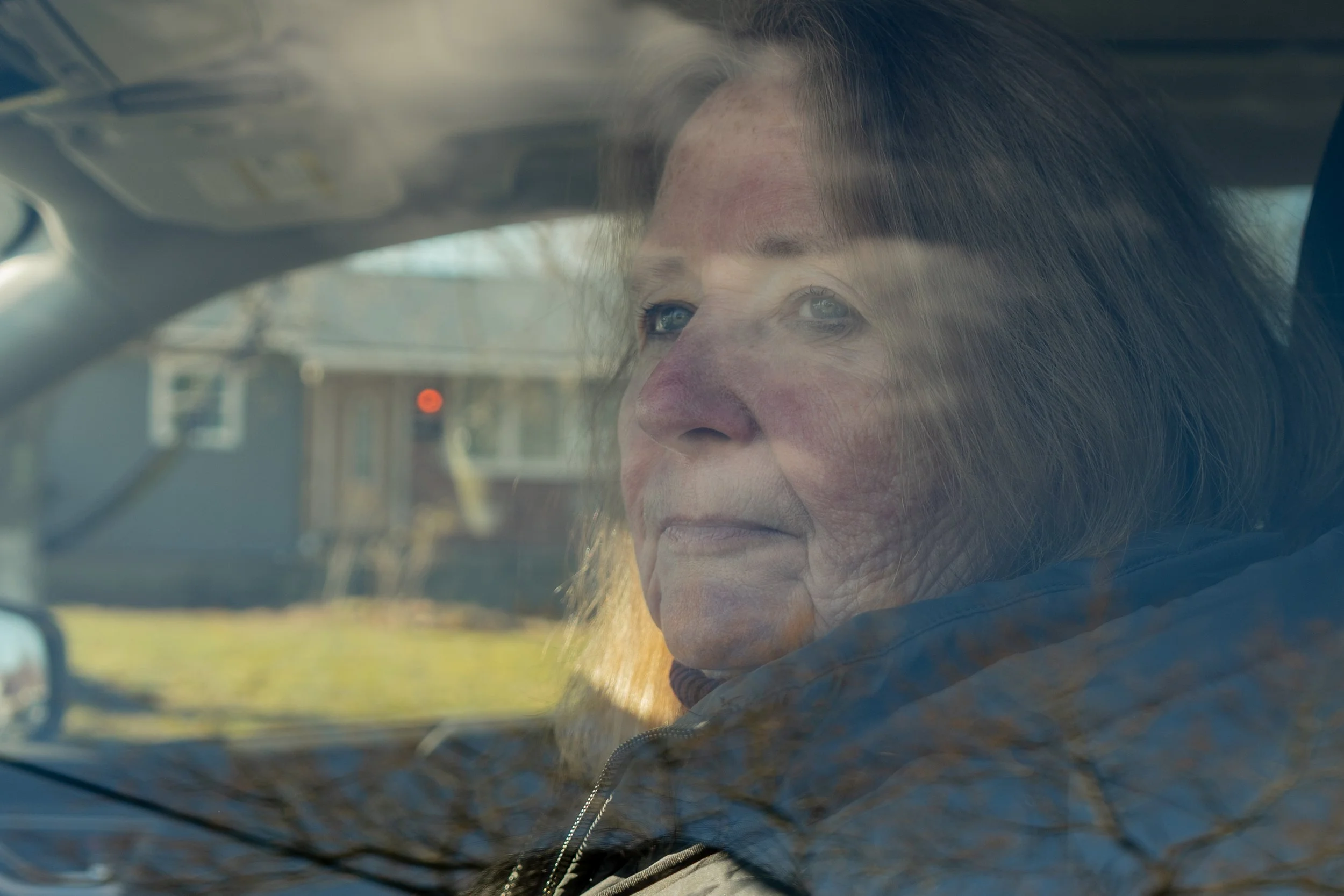 Linda Obernauer, a woman from Long Island, has been helping three children process their trauma after a warrantless ICE raid left them separated from their father. In this image, Linda looks out of a car window, outside the house that was raided.