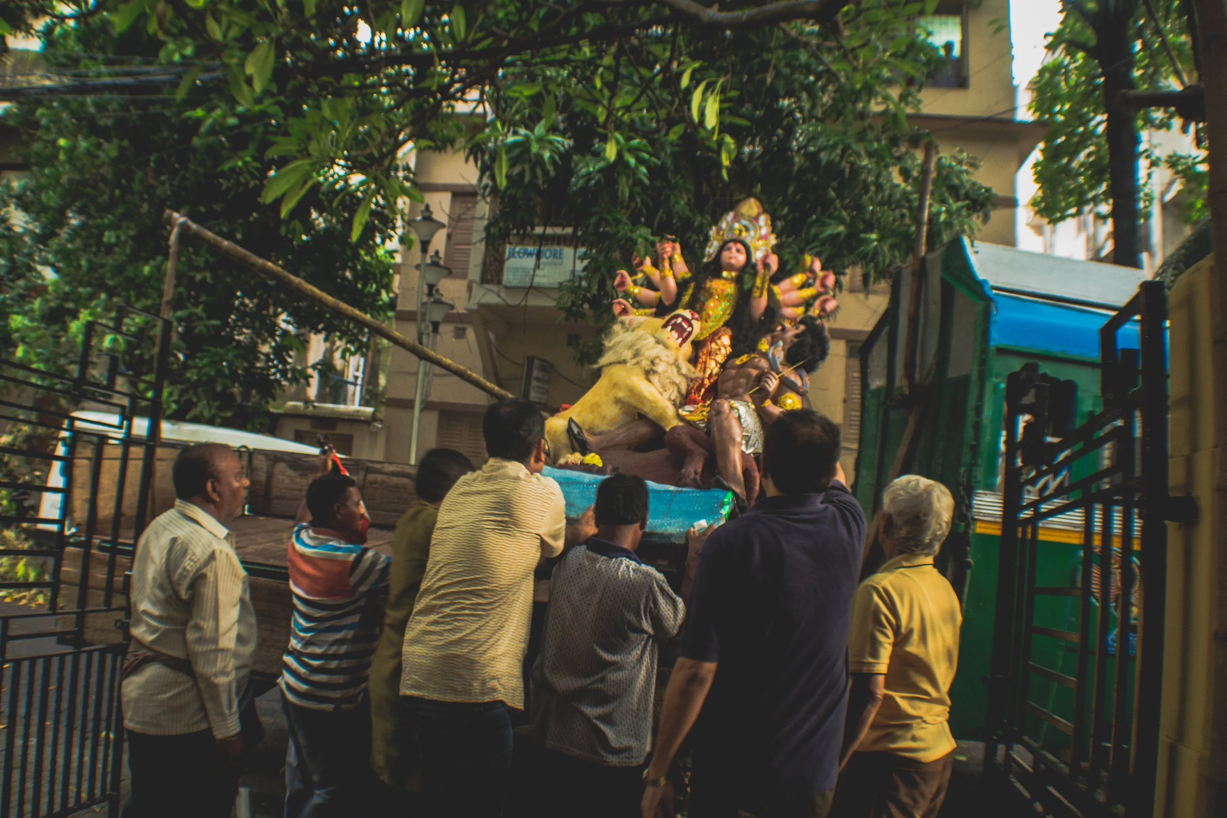 On the day of Bissarjan , family and friends of the Chatterjee family in South Kolkata heave a home idol onto a truck, to carry her to the Ganges.