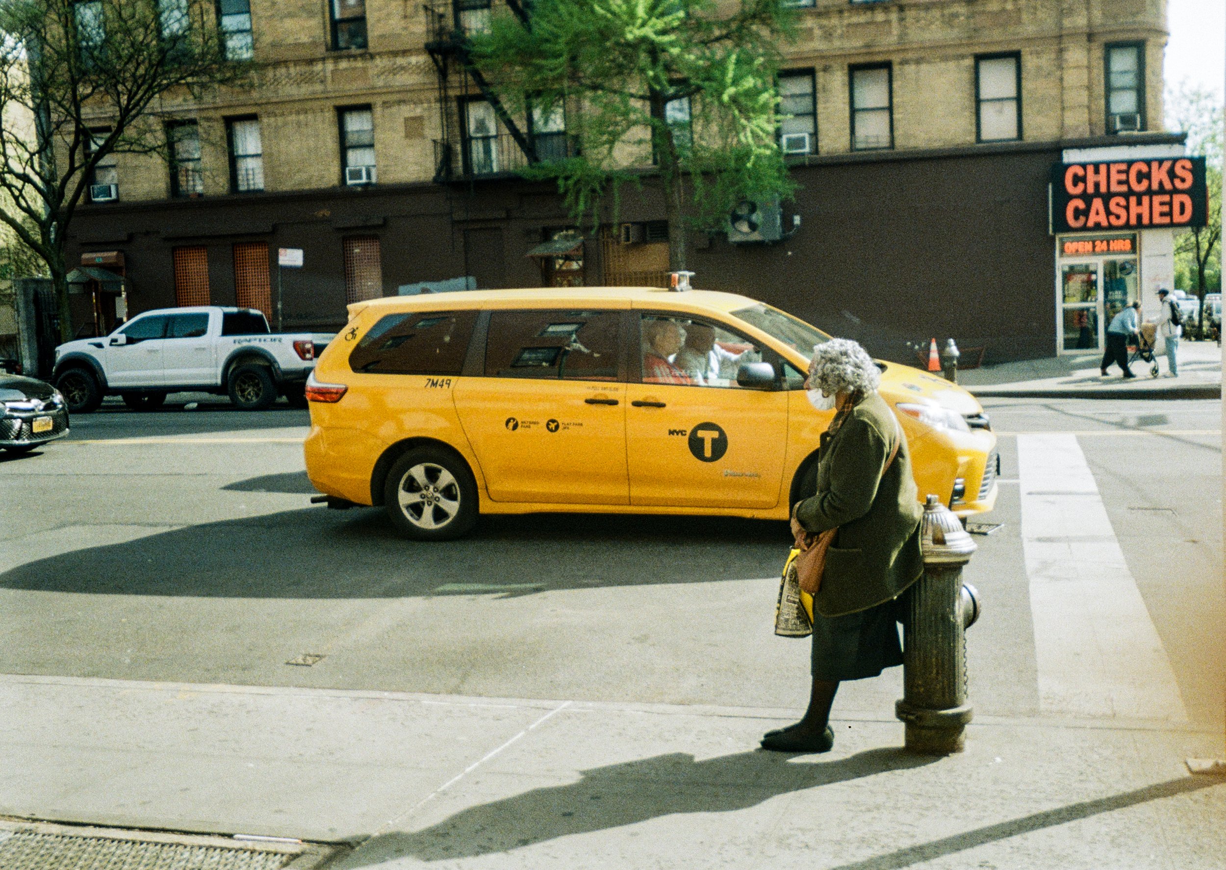 an elderly woman waits for the bus in east harlem, new york city. 