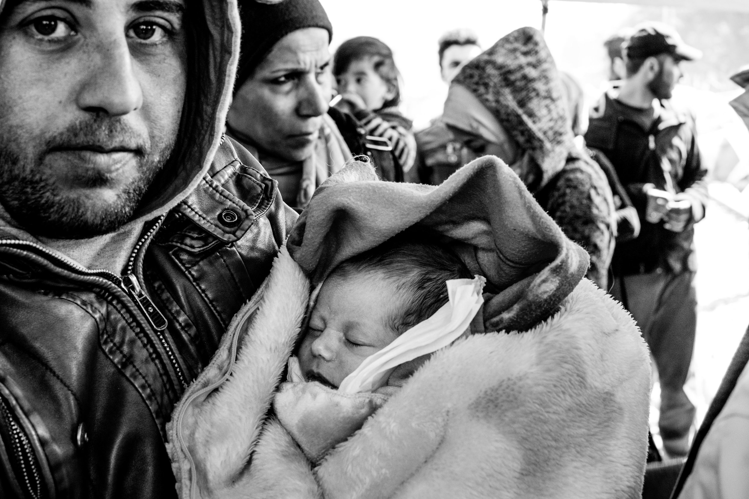 A baby is paraded around an area where media representatives swarmed with huge cameras draped over their shoulders.
