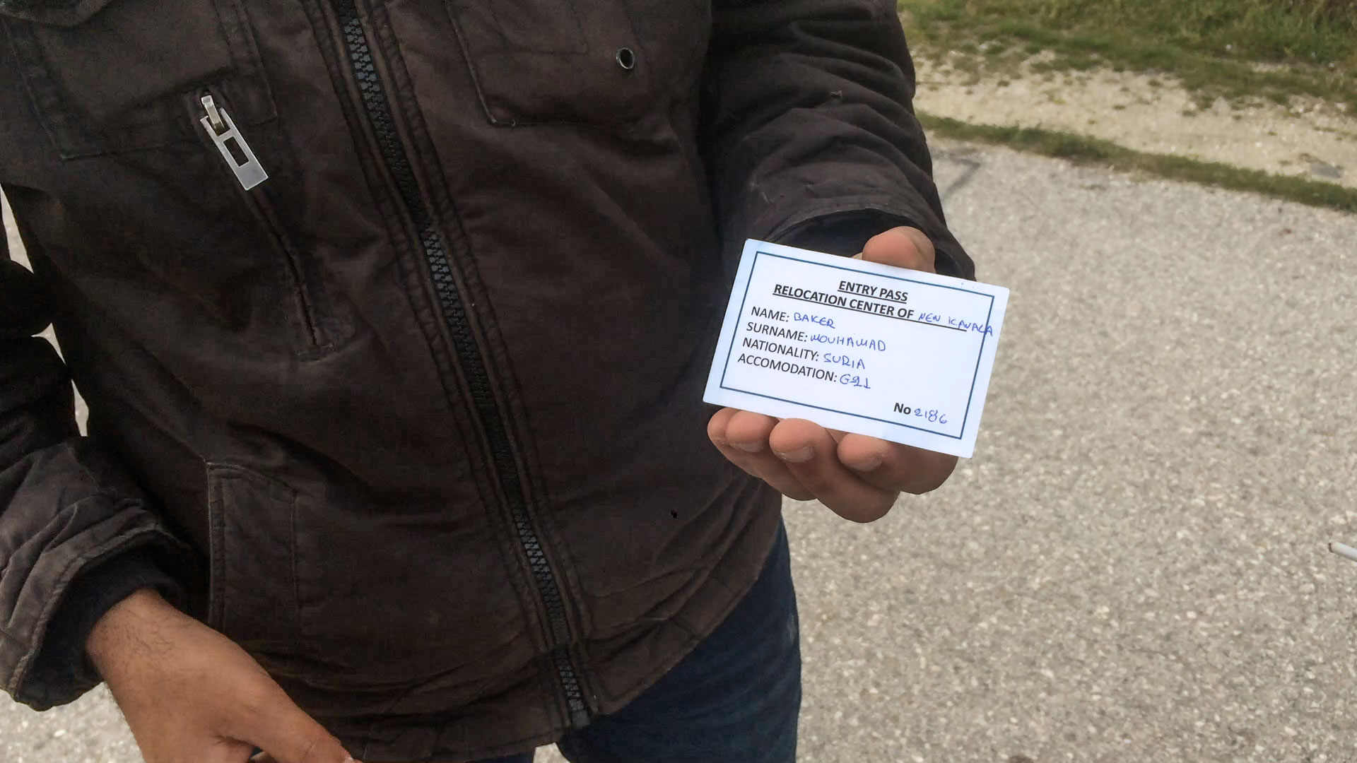 A Syrian refugee shows me his identification card for Nea Kavala camp, which is located on a military landing strip. It was heavily guarded by police and military.