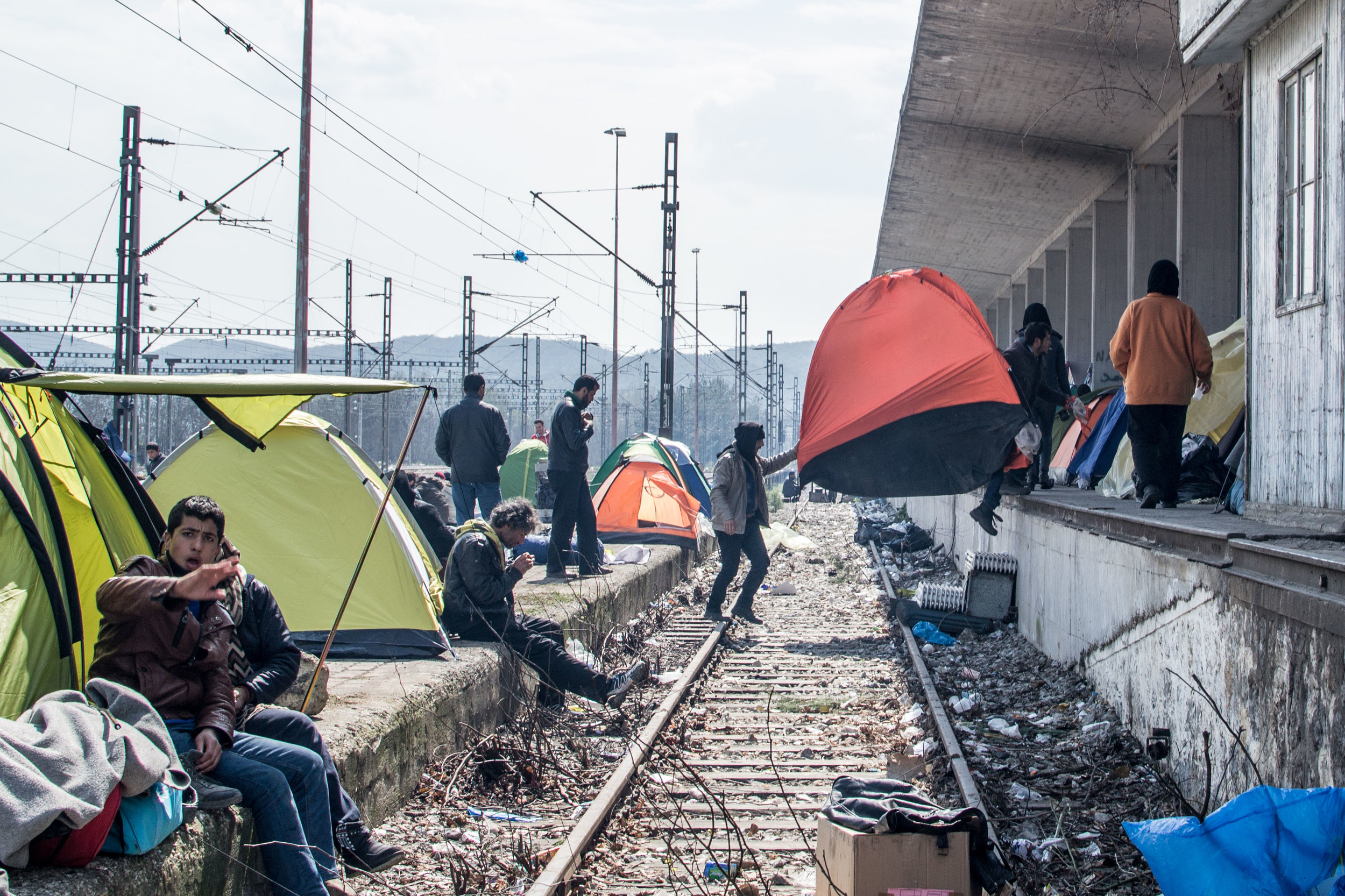 A family moves their tent across the abandoned rails of Eidomeni.