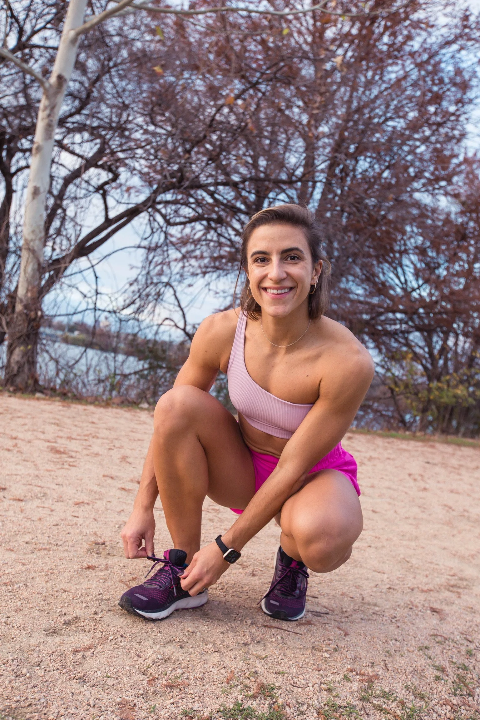 Tara smiling at the camera while bending down to tie her shoe.