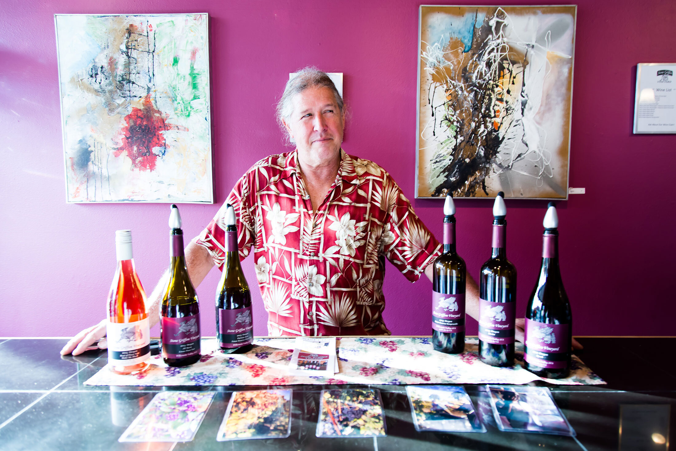 Owner Terry standing with a lineup of wine bottles