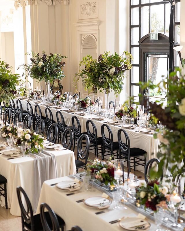 One of our favorite designs from last year. The luxurious black Portofino chairs and tall organic centerpieces had a beautiful mix of green and purple foliage bringing this moody and romantic look together which blended perfectly with the classical, 