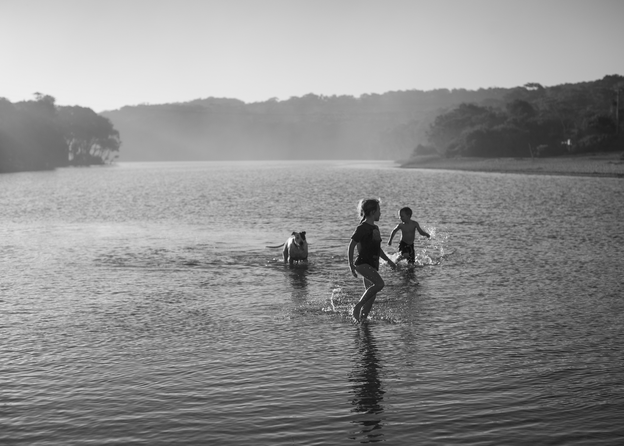 Kids running through lake with dog