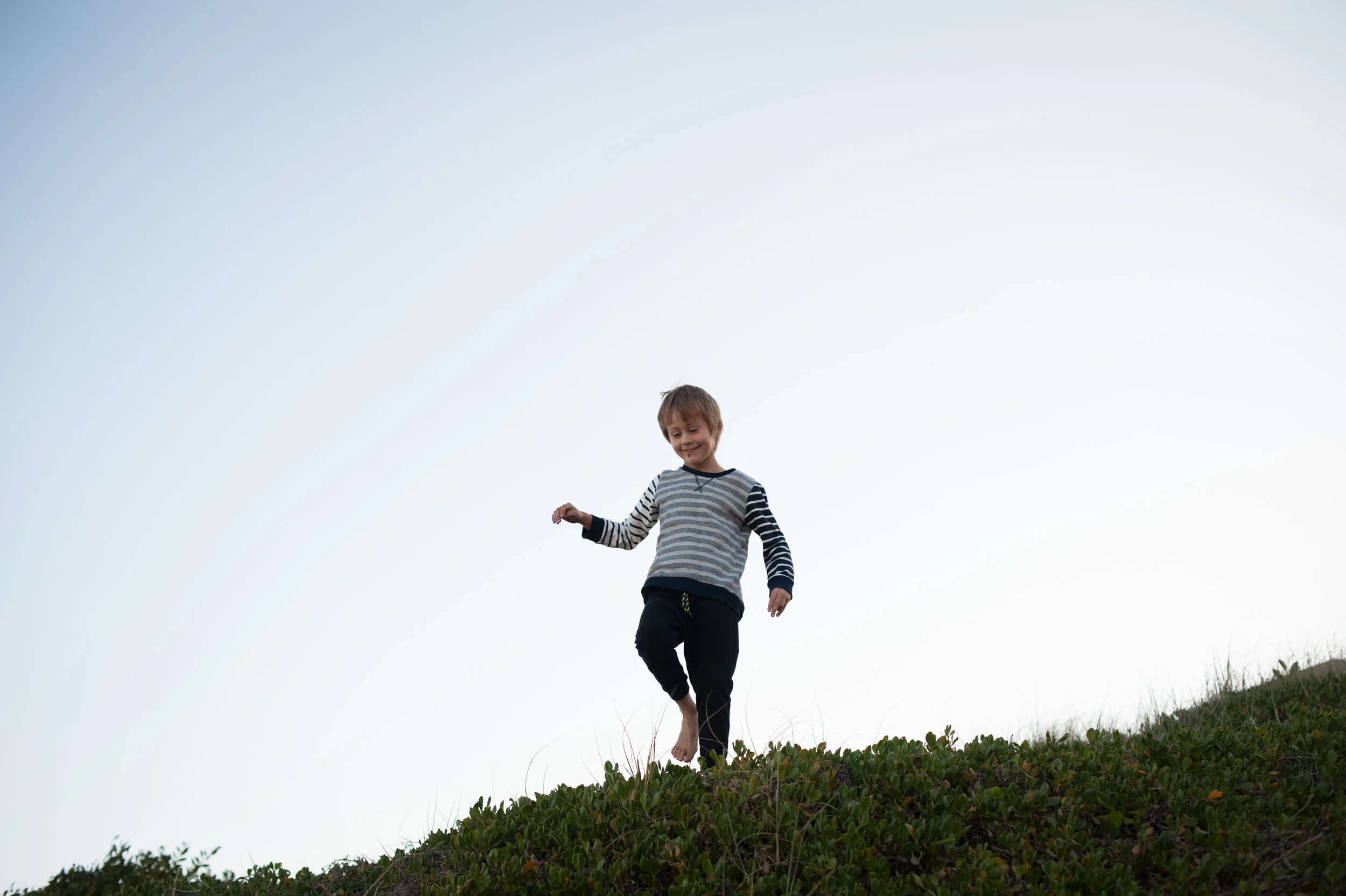 little boy running through sand dunes MacMasters Beach
