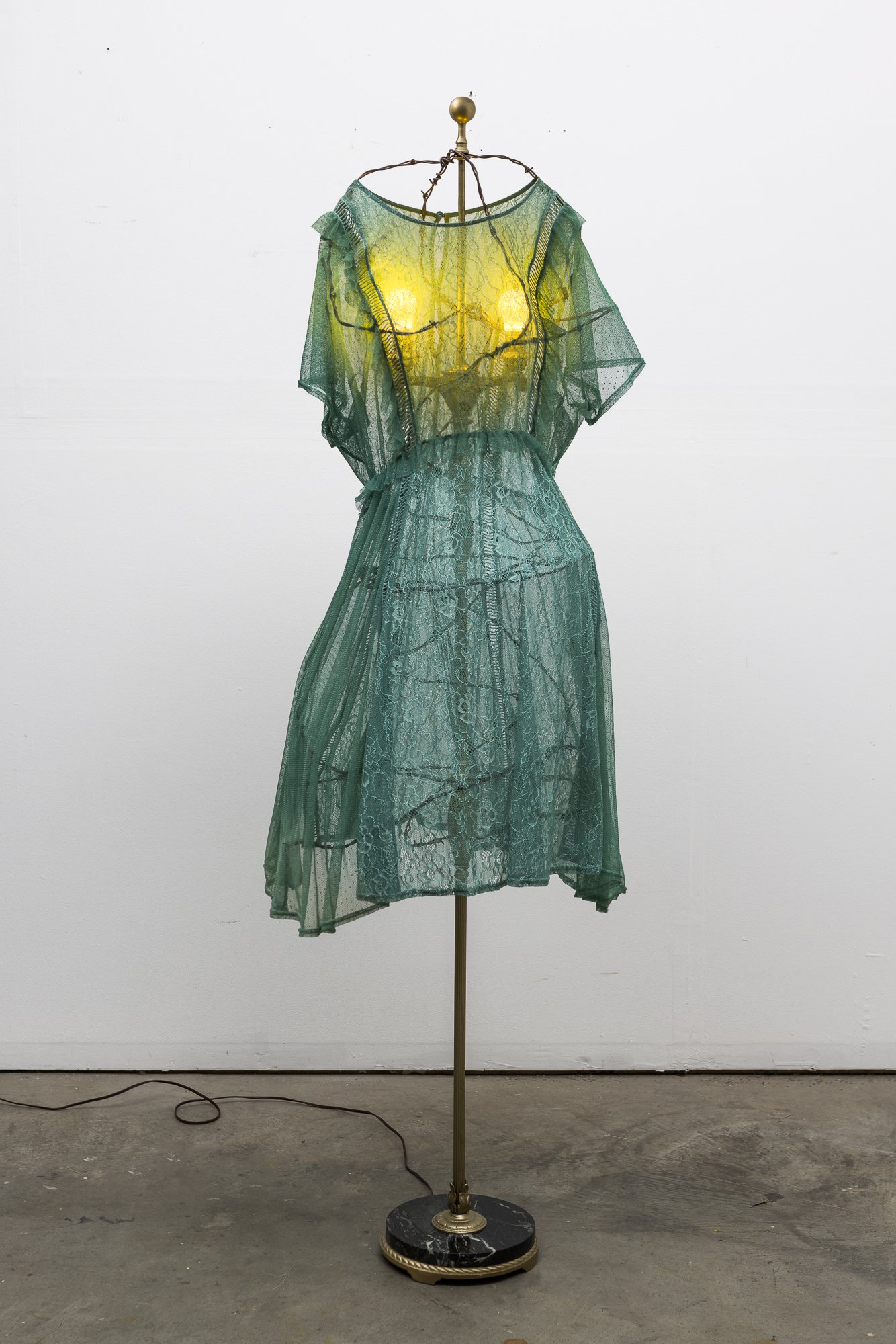  Nothing But A Woman, 2026, 68 x 20 x 18 inches, Dress, barbed wire, lamp, yellow light bulbs 