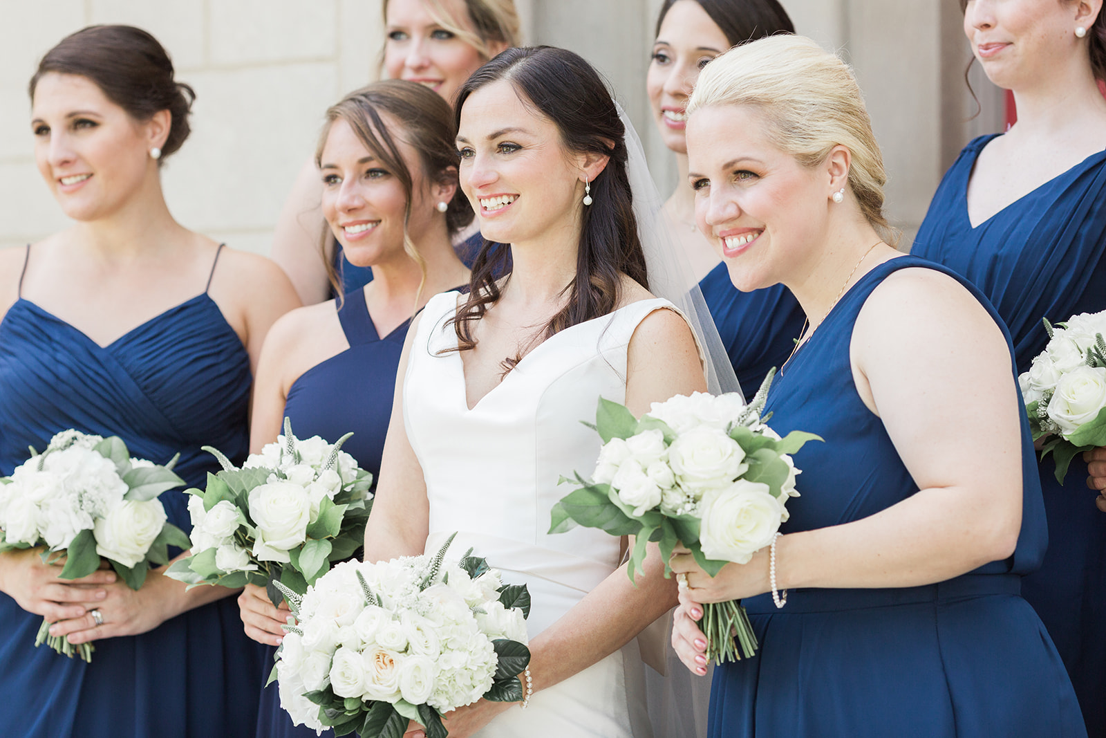 Bride with bridesmaids with blue dresses and white wedding bouquets pose for Pittsburgh wedding at PNC Park planned by Exhale Events. Find more wedding inspiration at exhale-events.com!
