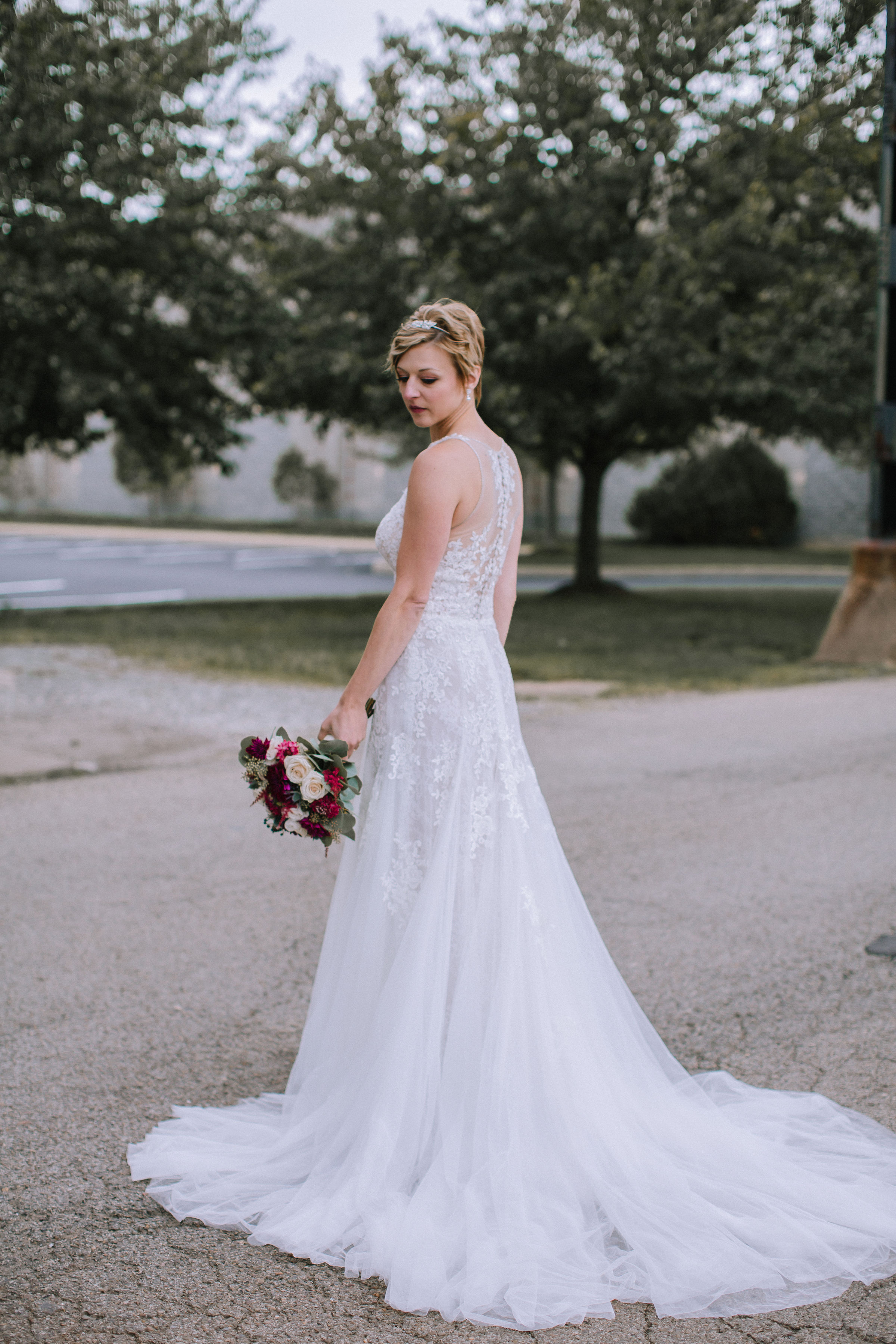 Brides showing wedding dress details with red wedding bouquet for Pittsburgh wedding at Studio Slate planned by Exhale Events. Find more wedding inspiration at exhale-events.com!