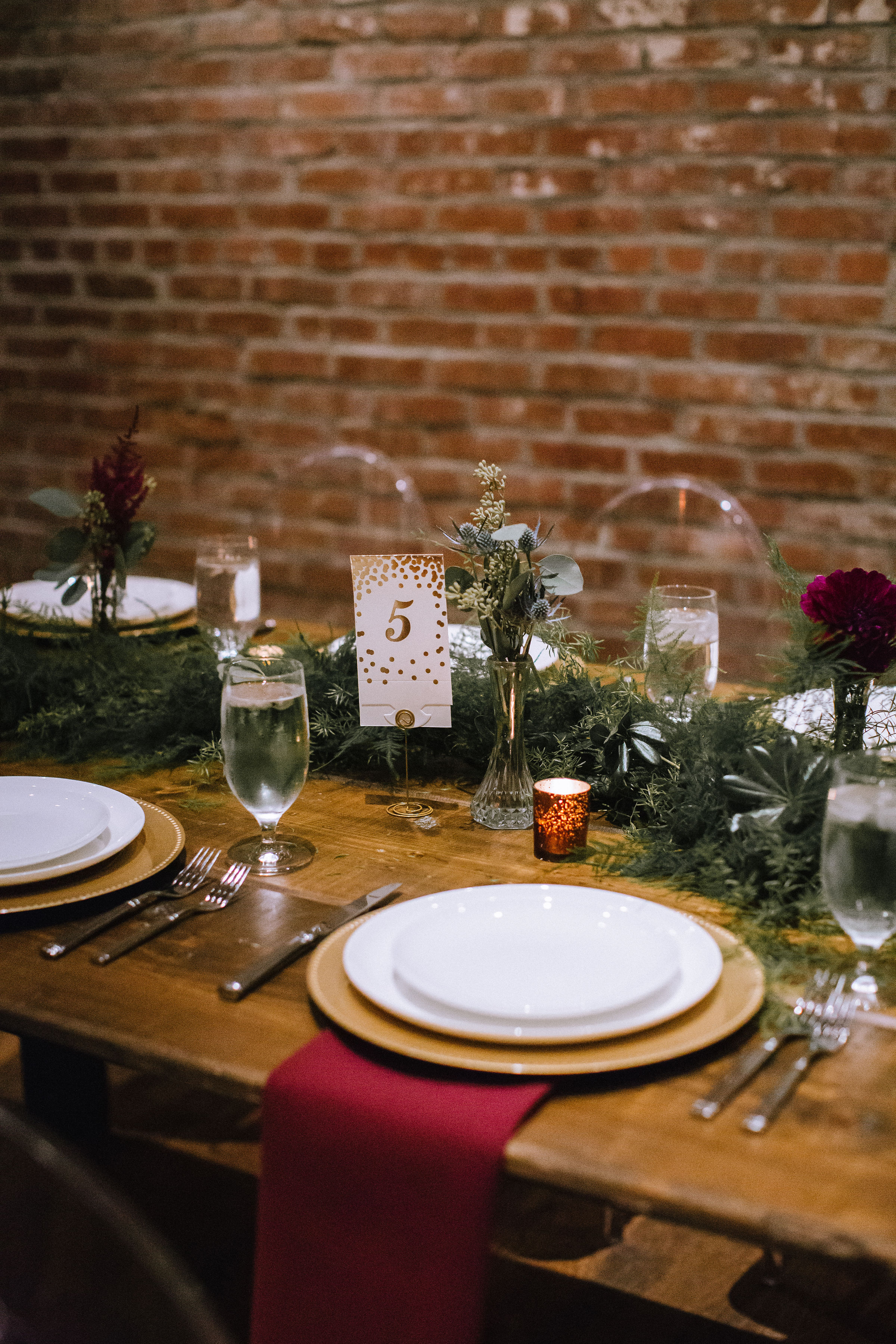 Wedding table setting and table decor with greenery and red and gold accents for Pittsburgh wedding at Studio Slate planned by Exhale Events. Find more wedding inspiration at exhale-events.com!
