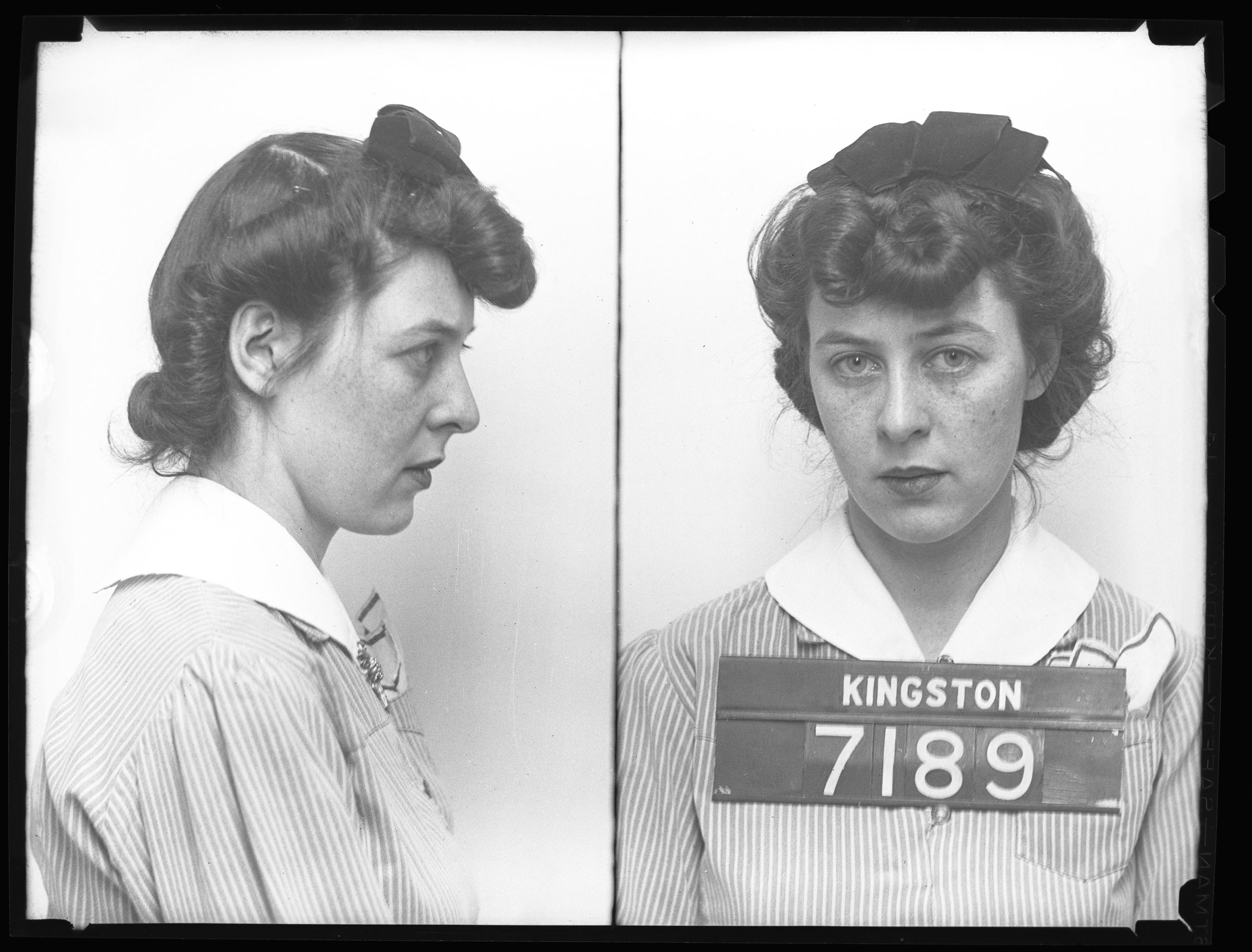 Arrival identification photograph (styled similar to a mug shot) showing front and side views of a woman wearing a striped dress with a white collar and a dark bow in her hair. The woman holds a placard labeled "KINGSTON 7189."