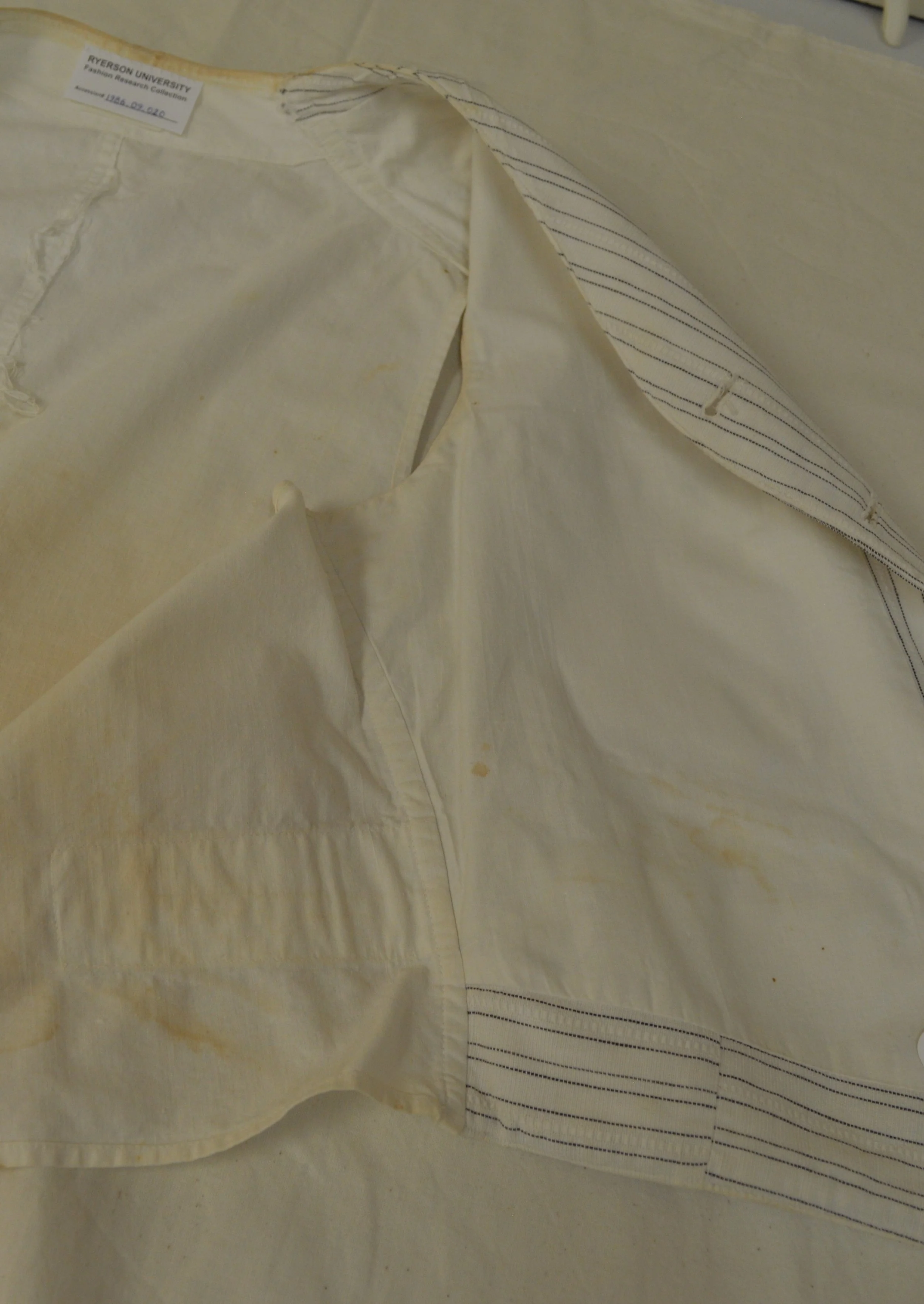 An interior view of the side and back panels of the pinstripe vest, showing yellow staining on the white fabric.