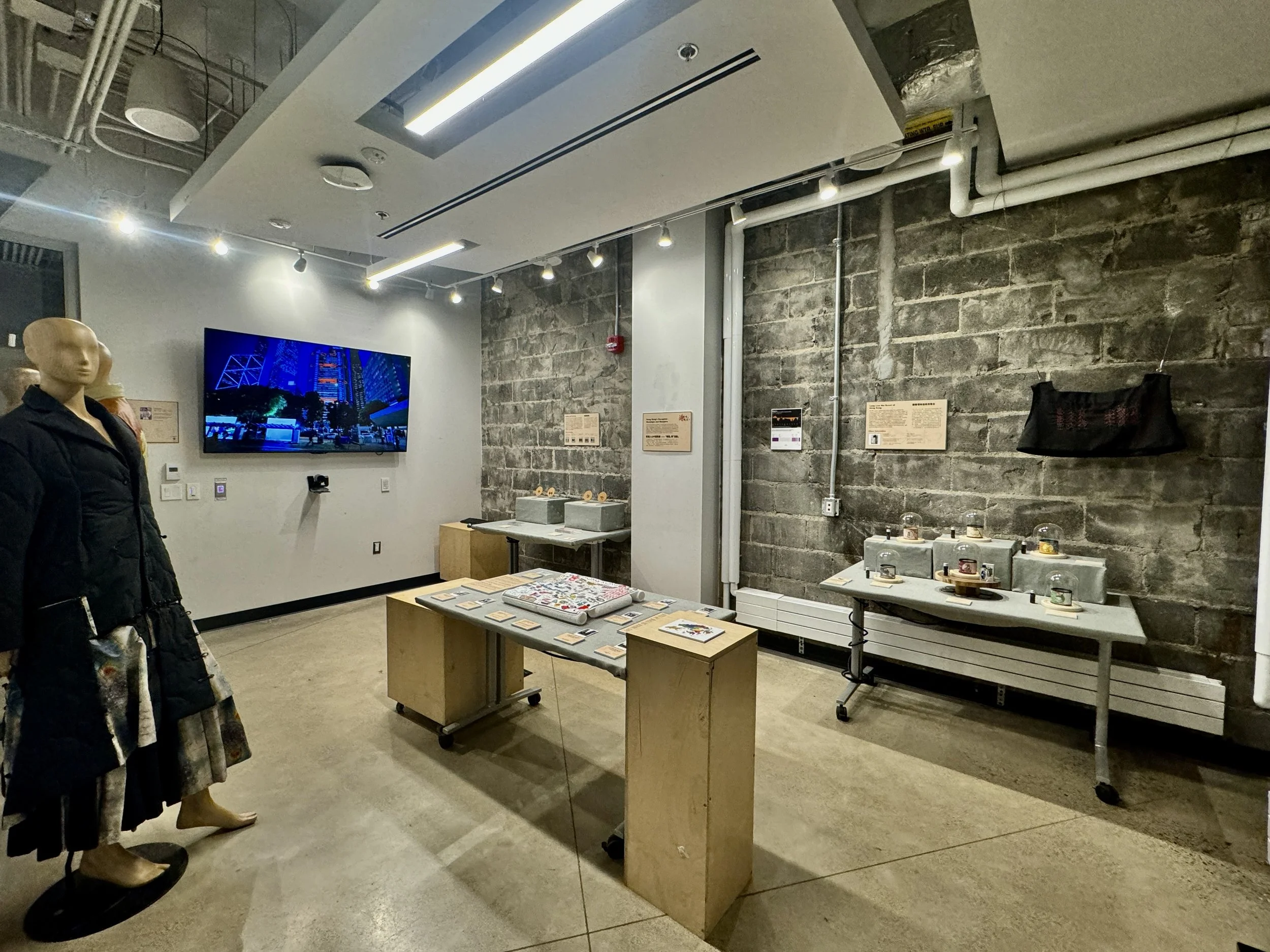 A photography showing the gallery space of the exhibition, The Postcolonial Hong Kong in the 2020s: A Prologue or an Epilogue?, from a ¾ angle From the left to right on the photography, there is a displayed mannequin in a black ensemble.