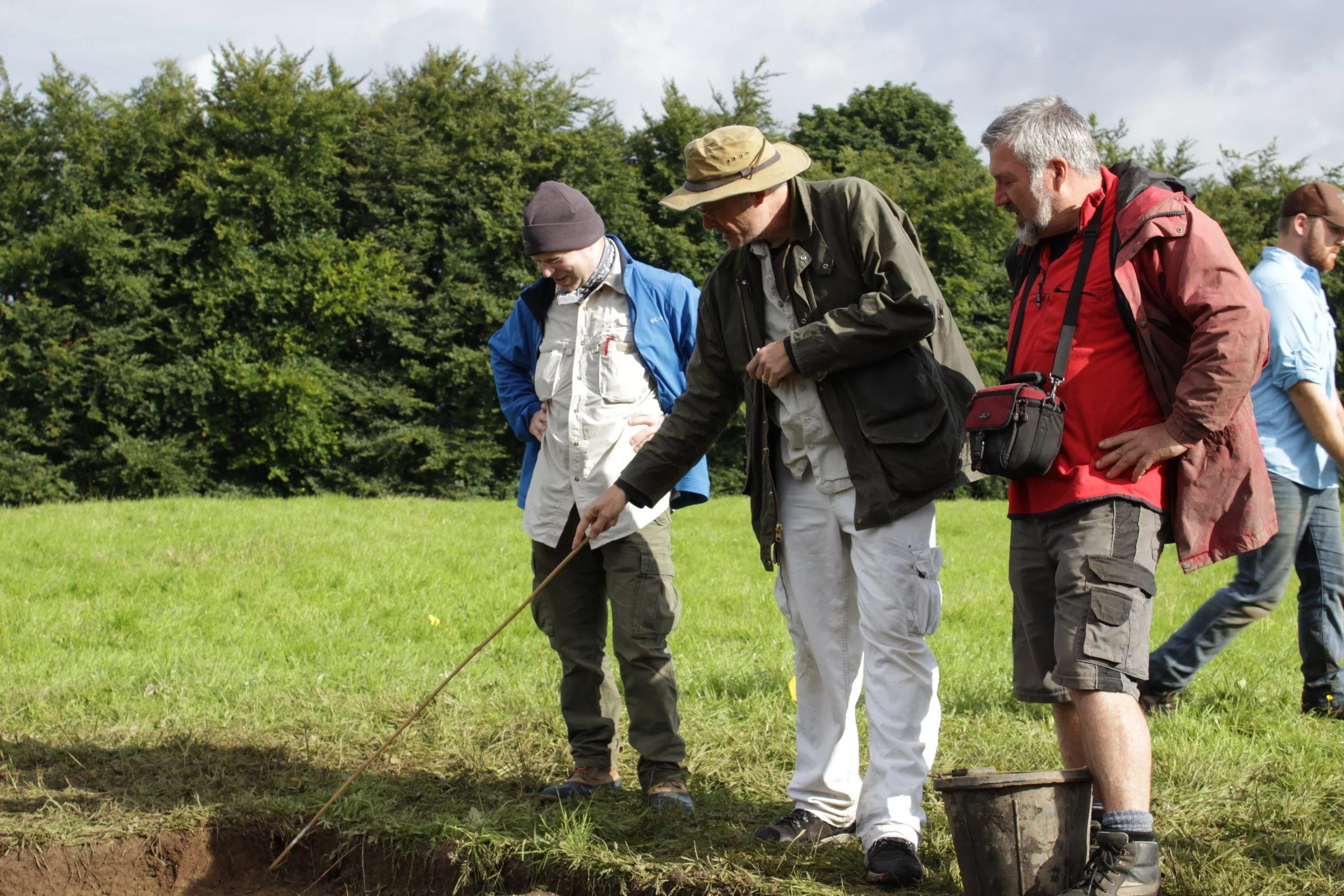 Archeologists Jim Shryver, Tom Finan and Alan Hayden discuss the stratigraphy of a test trench. (Photo credit: Arianna Riggs)