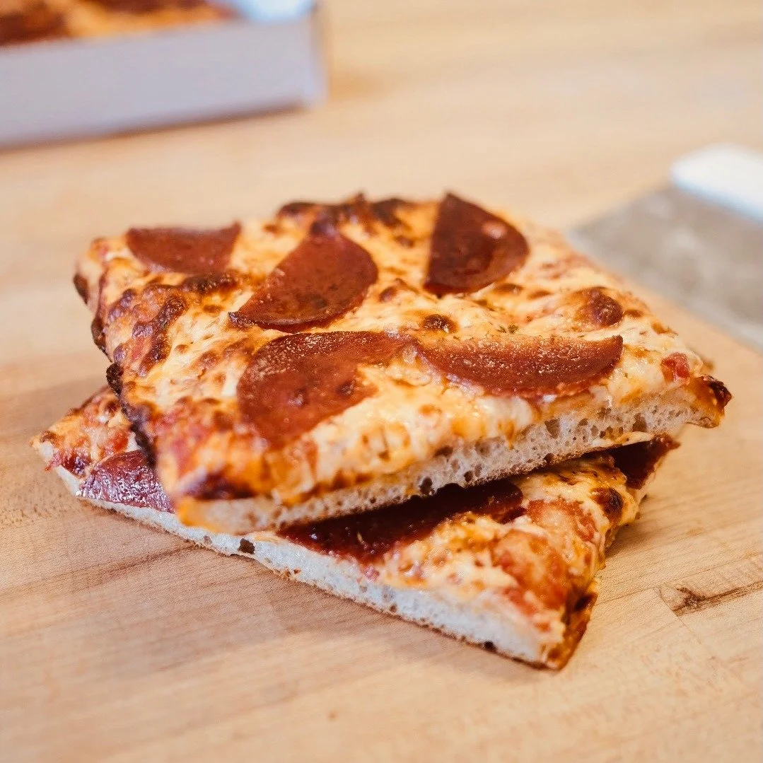 Happy Thursday.
Weekend plans, handled.
The cases are full, the bread is fresh, hot cross buns are back for the season, and focaccia pizzas are available for Friday pickup.
Our pizzas are old-school Sicilian style &mdash; crispy focaccia base, bubbly