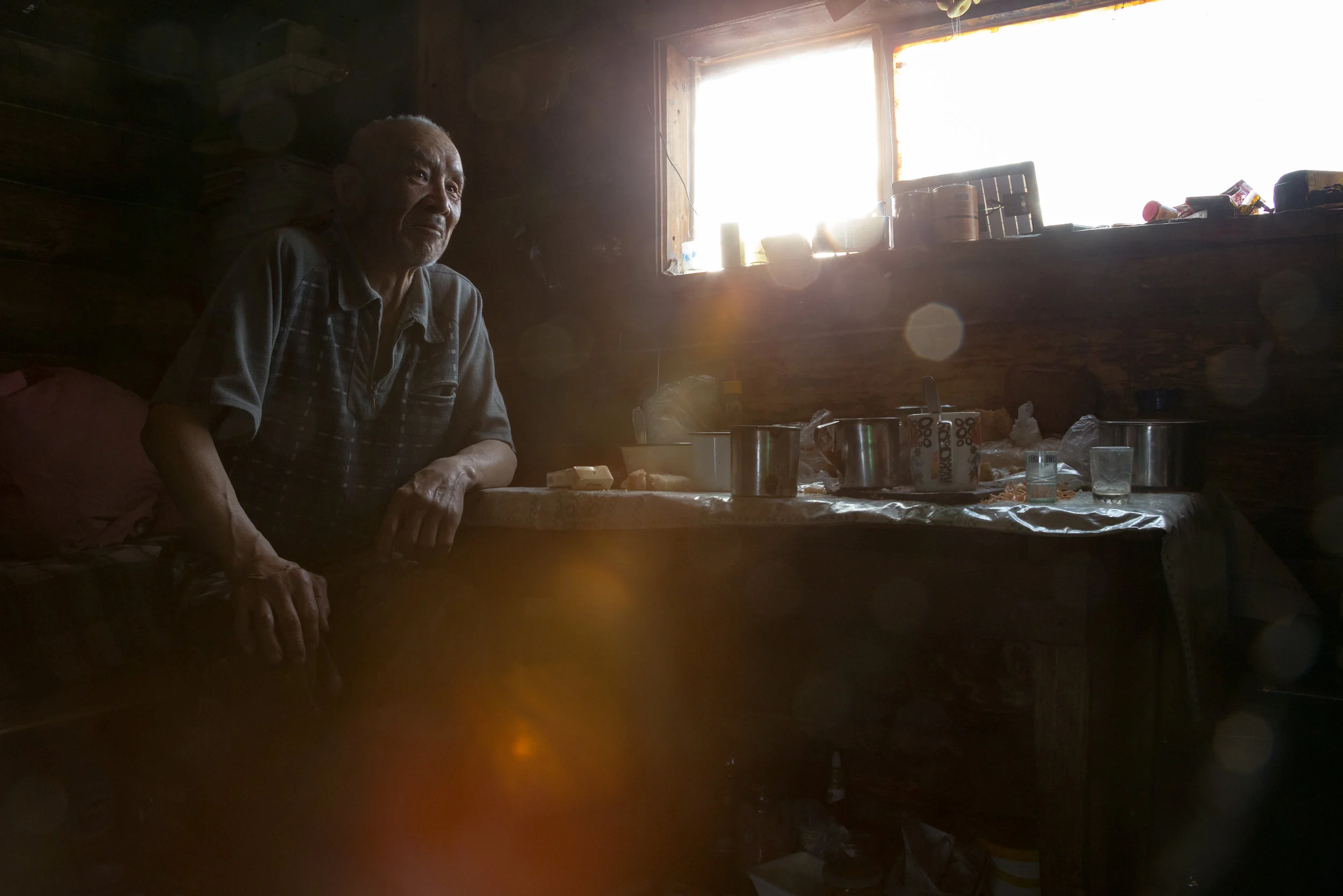 An ethnic Even man sits on his bed in his one room cabin in the backcountry. Bystrinsky District, Kamchakta, Russia. 