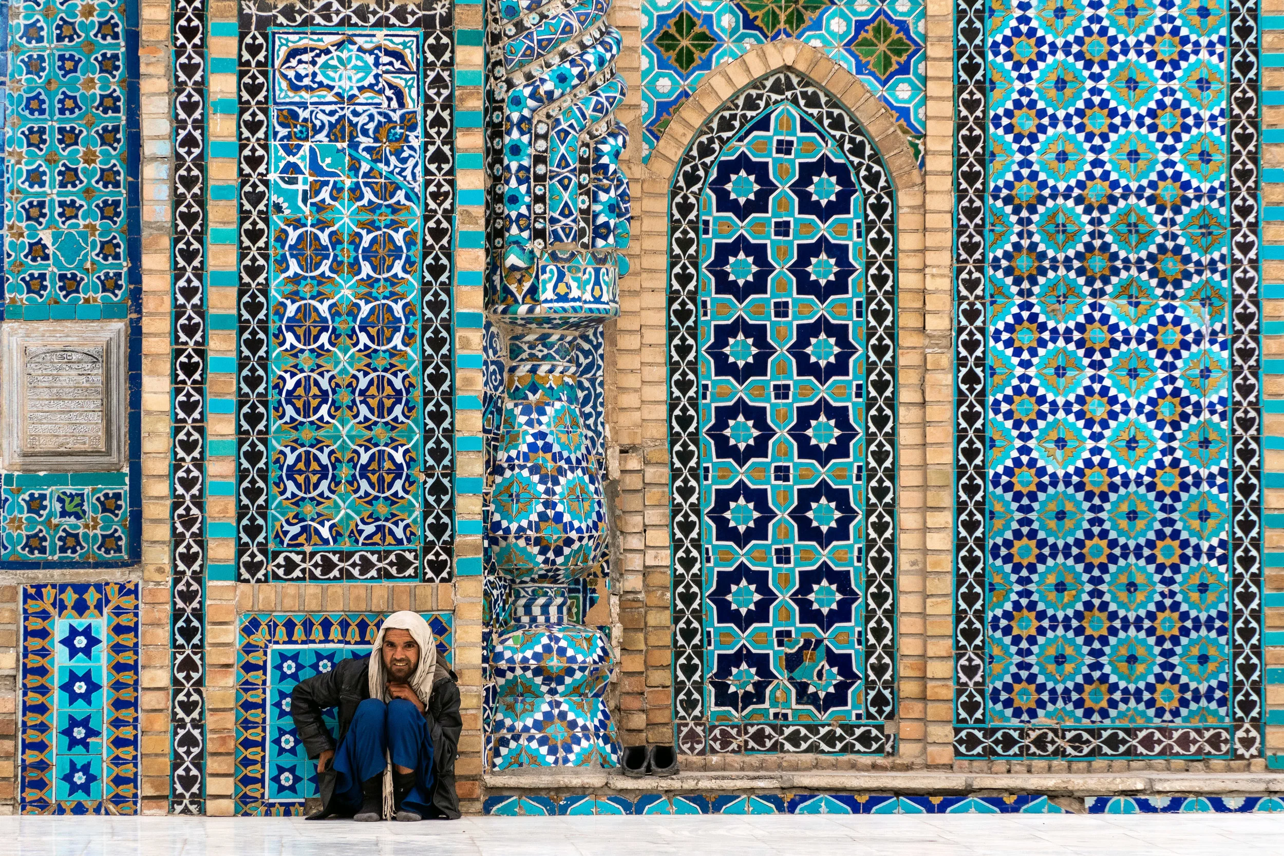 A man takes a rest against a colourful mosaic wall at the Blue Mosque in Mazar-i-Sharif.