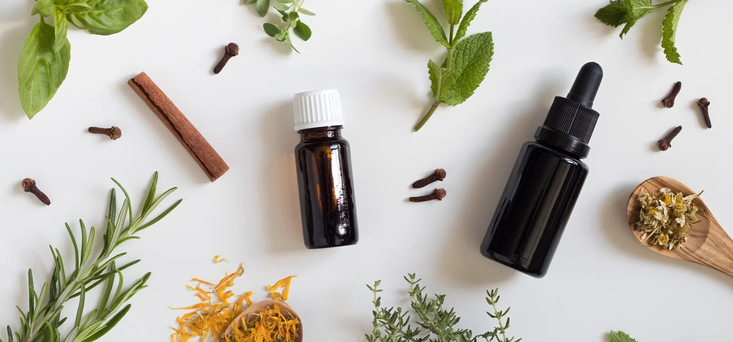Two-bottles-of-essential-oil-with-a-selection-of-herbs-on-a-white-background.jpg