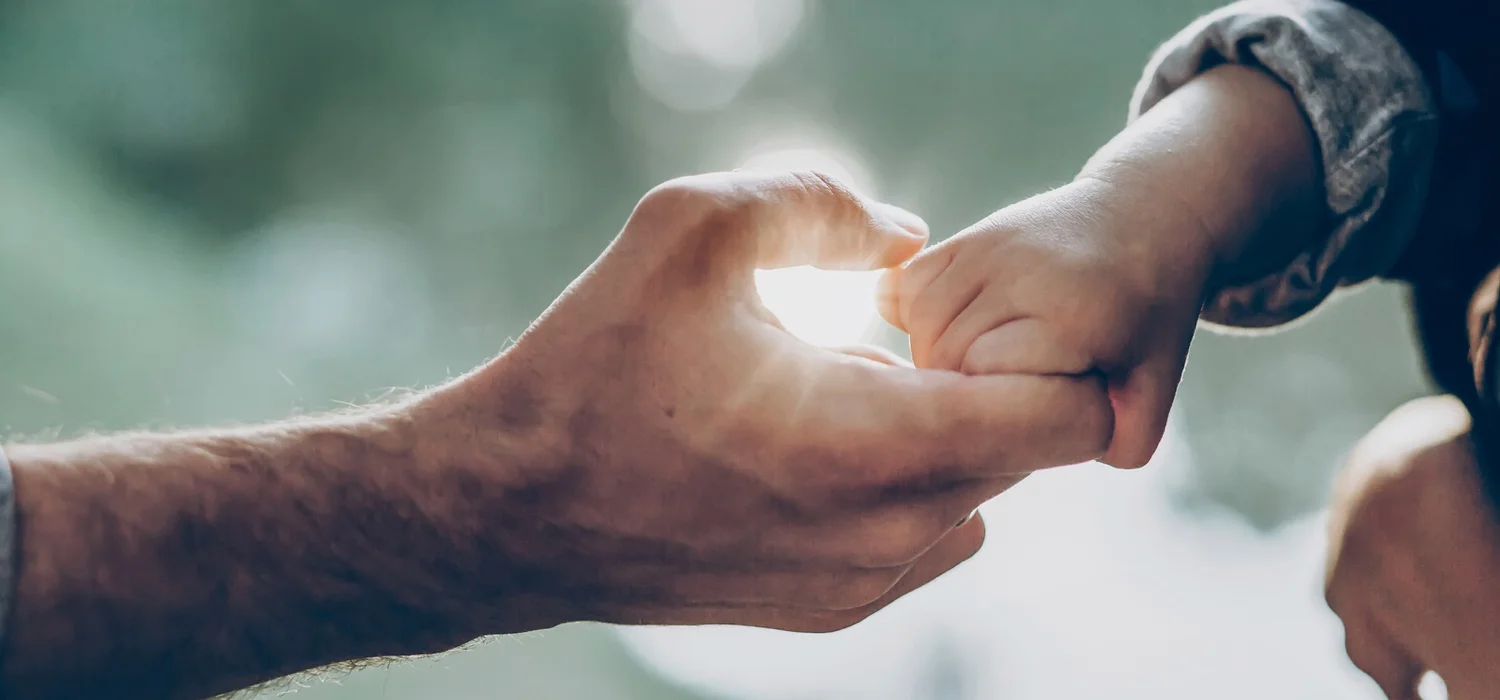 Father-holding-child's-hand-with-sunshine-light-on-backgroundf.jpg