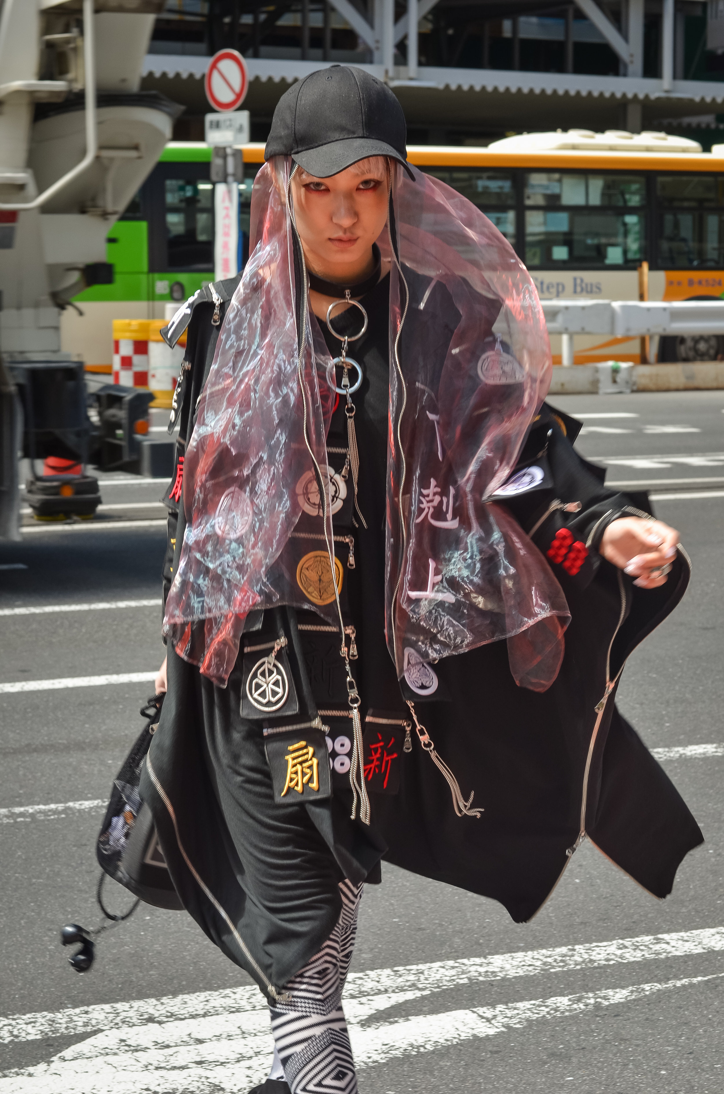 Her pink veil acts as an oxymoron, providing purity in a outfit with goth undertones. (日本語のキャプション: ジッパーはタイタンの力を持っている。服に書いてある言葉は神の言語だ。)