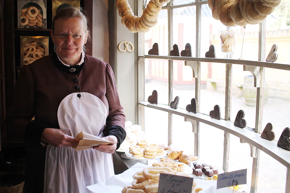 BAKERIET: Denne hyggelige dama jobber i det gamle bakeriet. Der baker hun kaker slik de gjorde i gamle dager. Kakene er til salgs. Foto: Tenk Koffert