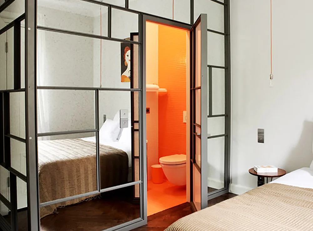 KULT HOTELL: Veggen inn til det knalloransje badet hos Between Us B & B er av speil. Og lobbyen på hotellet blir til et kult utested på kvelden. Foto: Hedda Bjerén